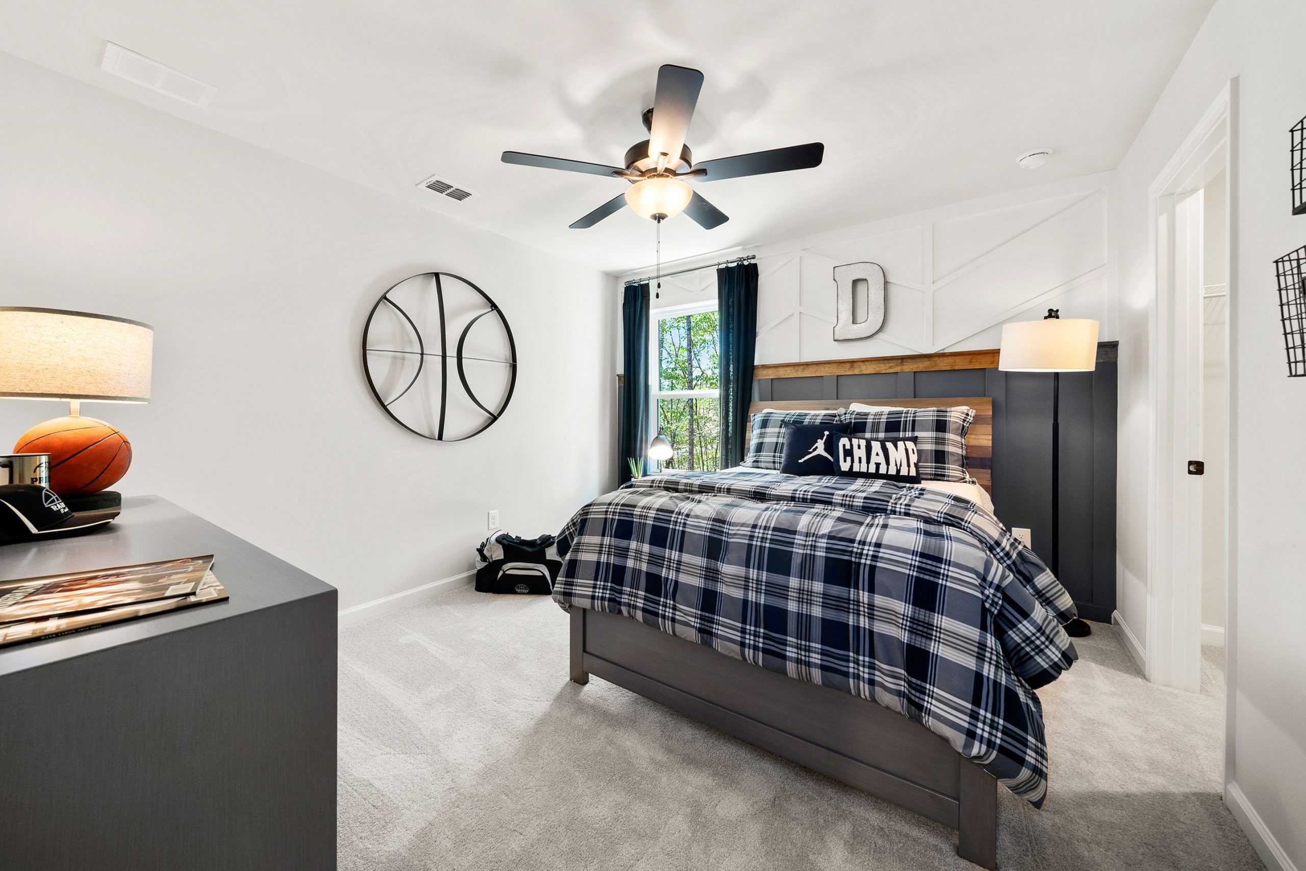 Basketball-themed boy's bedroom at Riverwood in Dallas, GA with twin bed, plaid bedding, wall hoop, and ceiling fan