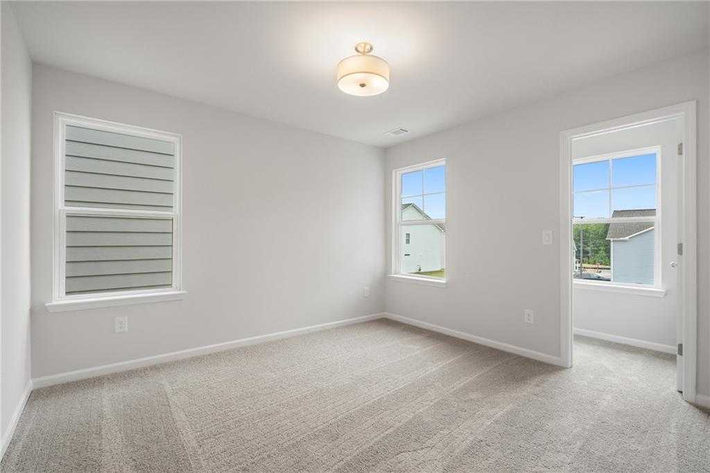Bright secondary bedroom with light gray walls, large sunny windows, and plush carpet in Davidson Homes The Cary A, Kennesaw, Georgia