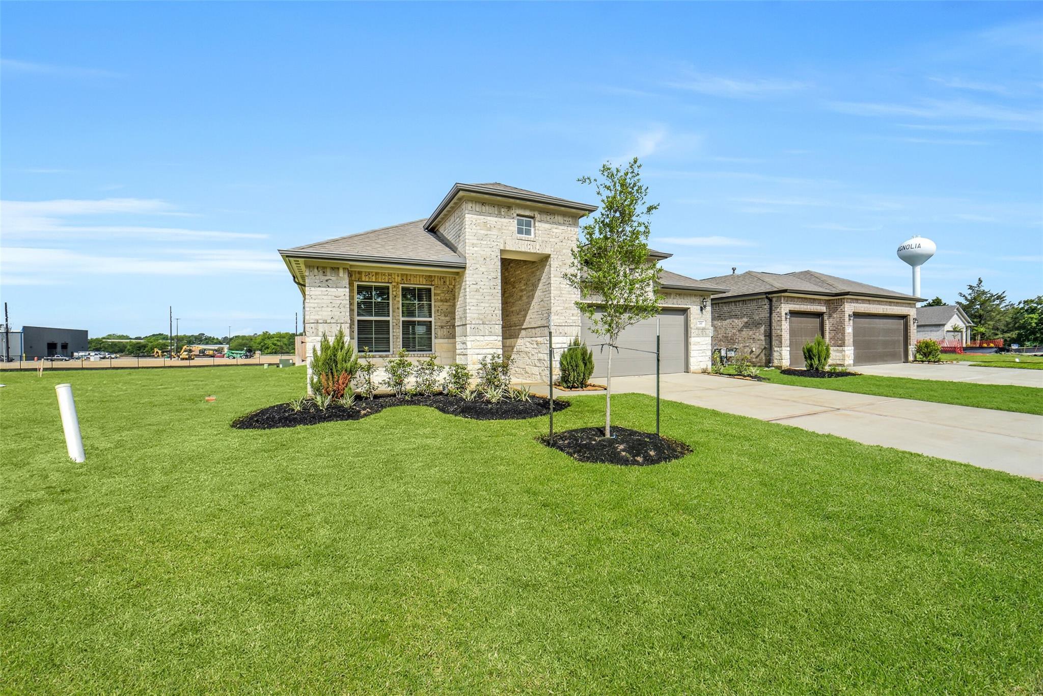 Brick 1-story 4-bedroom home with 2-car garage, landscaped yard, and Magnolia water tower in Windmill Estates, Texas