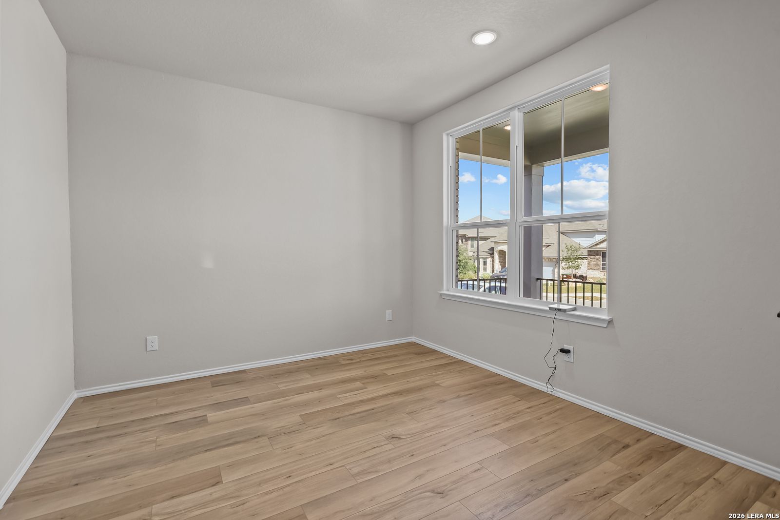 Bright empty bedroom with wood-look tile flooring and large window in Davidson Homes The Sequoia C, Royal Crest, San Antonio, Texas