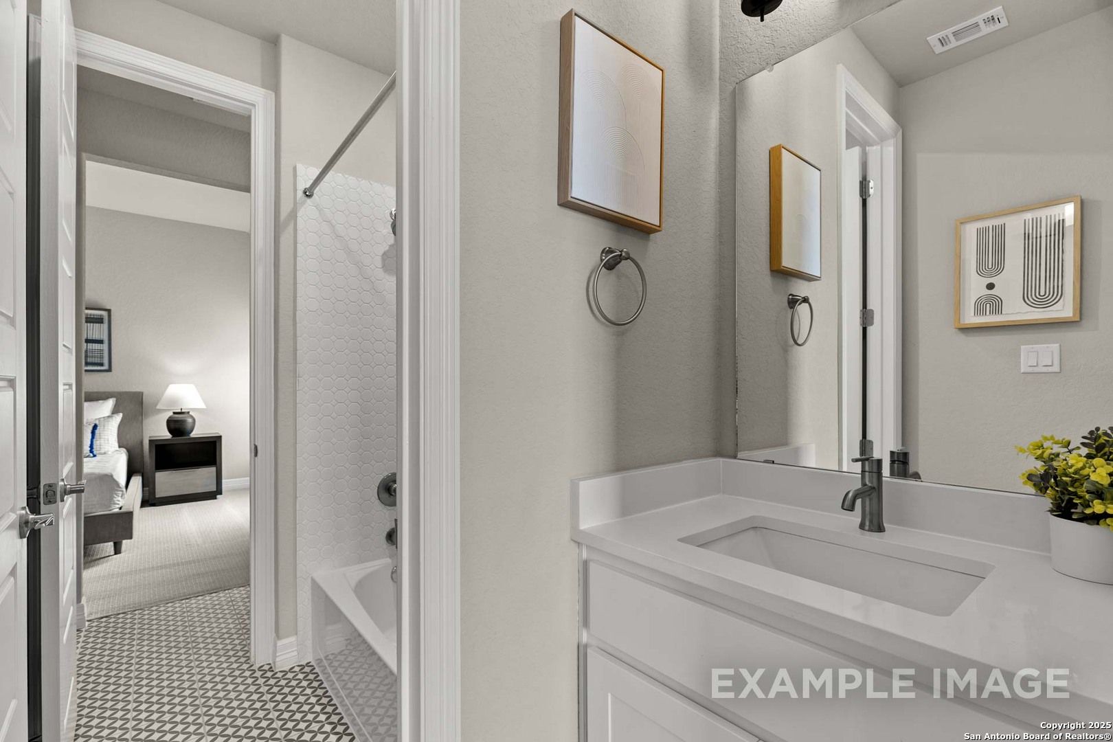 Modern bathroom with walk-in shower, vanity sink, and mirror adjacent to cozy bedroom in Davidson Homes The Summerlin B, Castroville TX