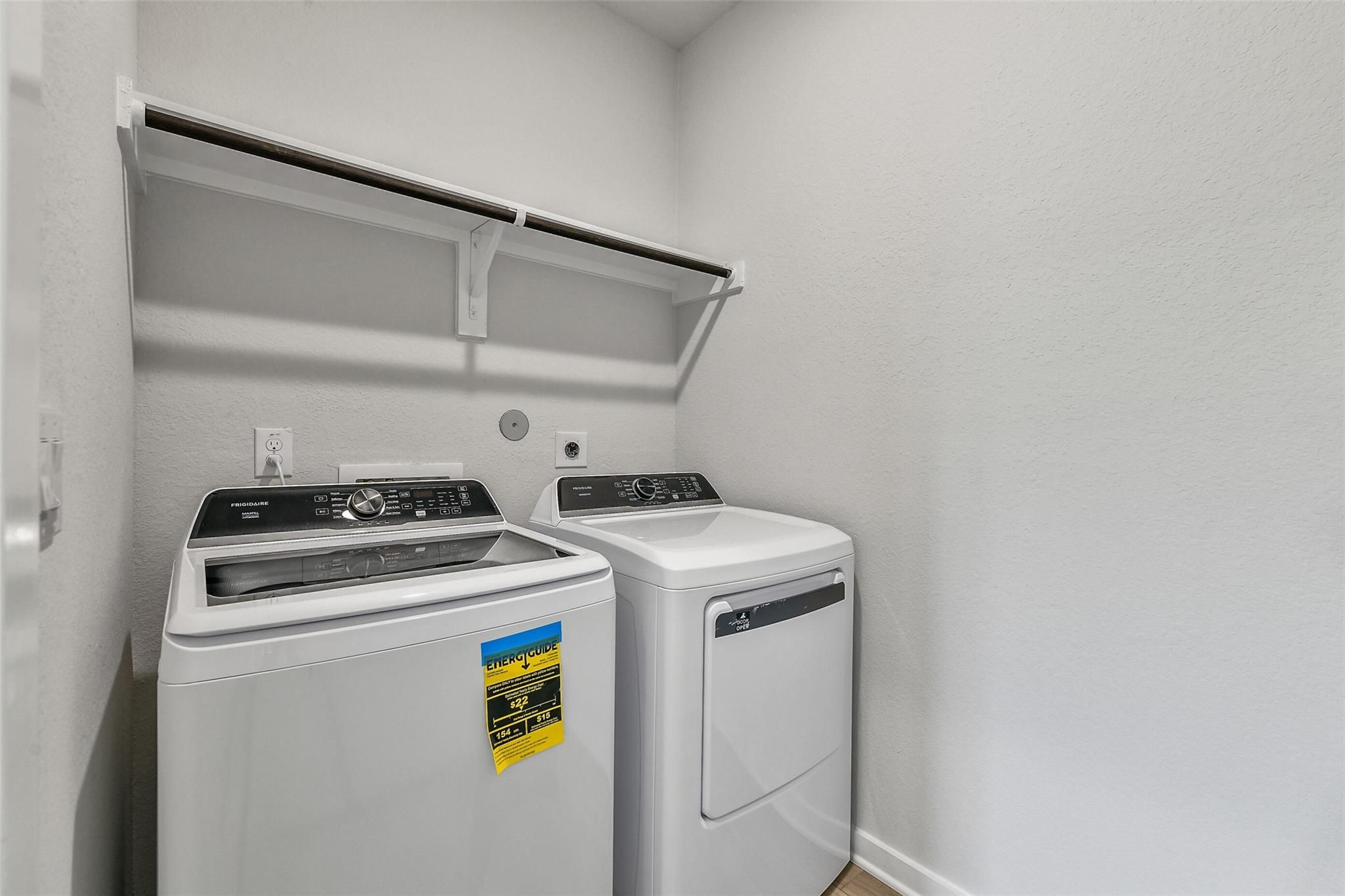 Spacious laundry room with white front-load washer, dryer and built-in shelves in Davidson Homes The Colorado G, Magnolia, Texas