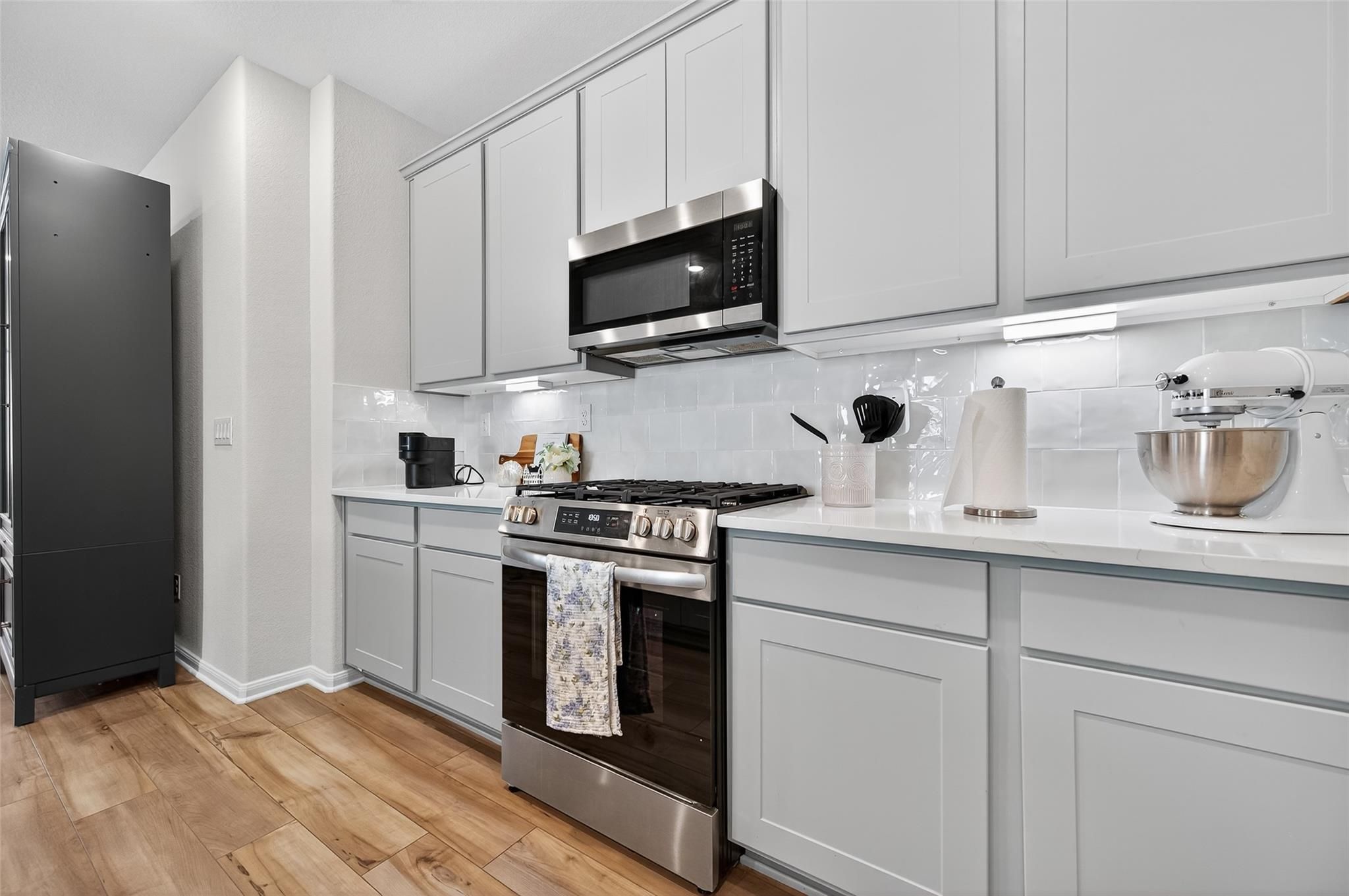 Modern white shaker kitchen with stainless steel appliances, quartz counters, and subway tile backsplash in Brazos E home, Magnolia, TX