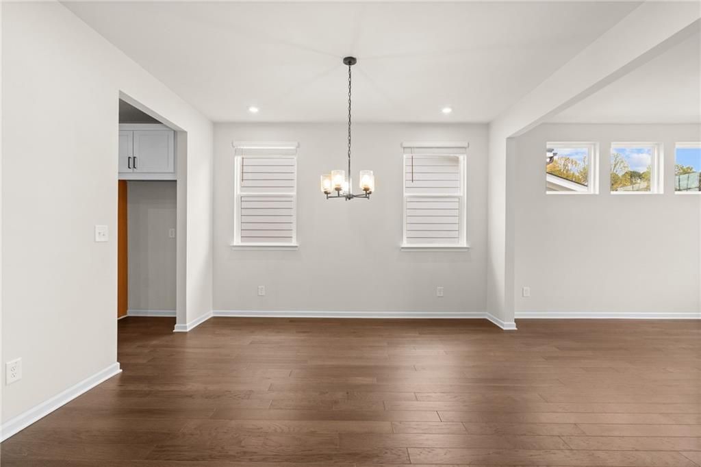 Elegant dining room with hardwood floors, chandelier, and shuttered windows in The Glenwood A, Kelly Preserve, Loganville, Georgia