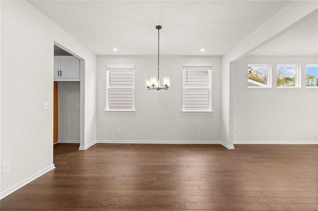 Elegant dining room with hardwood floors, chandelier, and shuttered windows in The Glenwood A, Kelly Preserve, Loganville, Georgia
