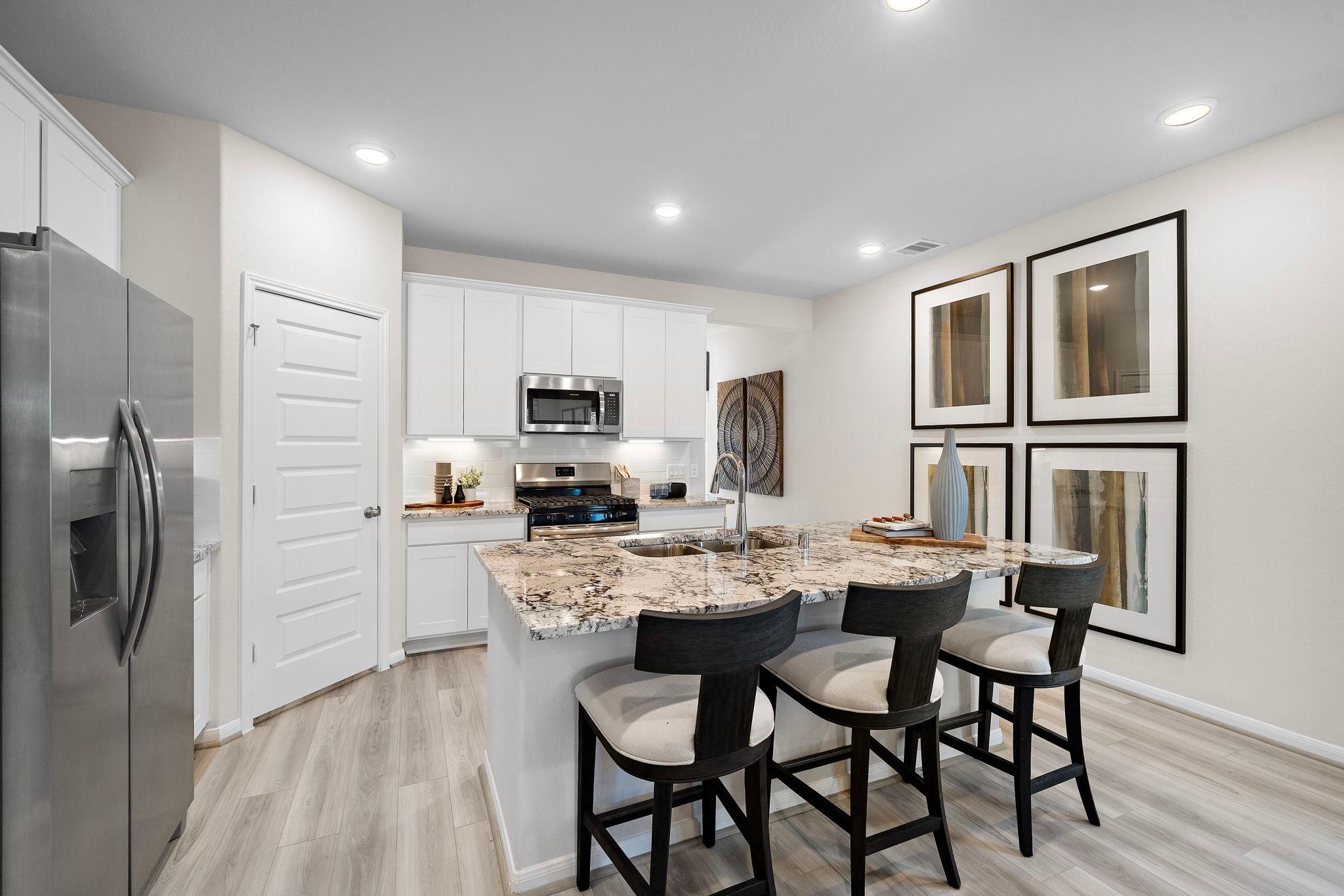 Spacious kitchen with white shaker cabinets, granite island, stainless steel appliances, bar stools at Lakes at Black Oak in Magnolia, Texas