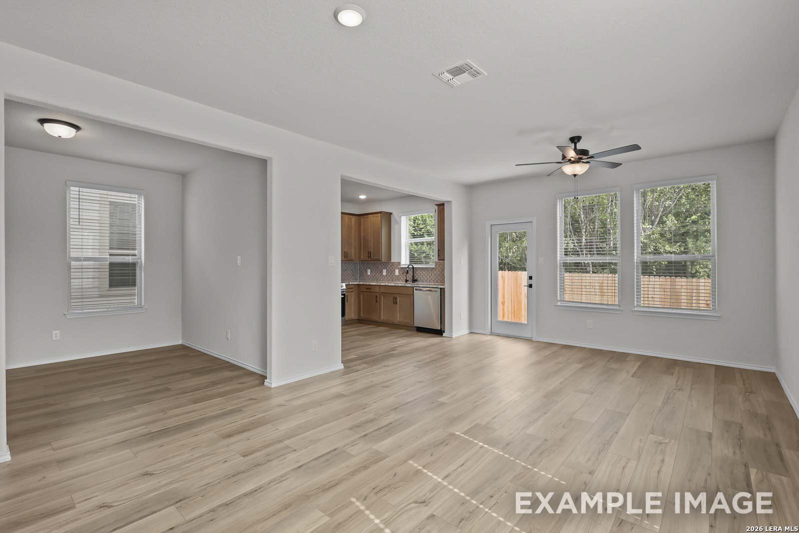 Open-concept living area with wood-look flooring and kitchen view in The Florence D floor plan, Cedar Heights, San Antonio.