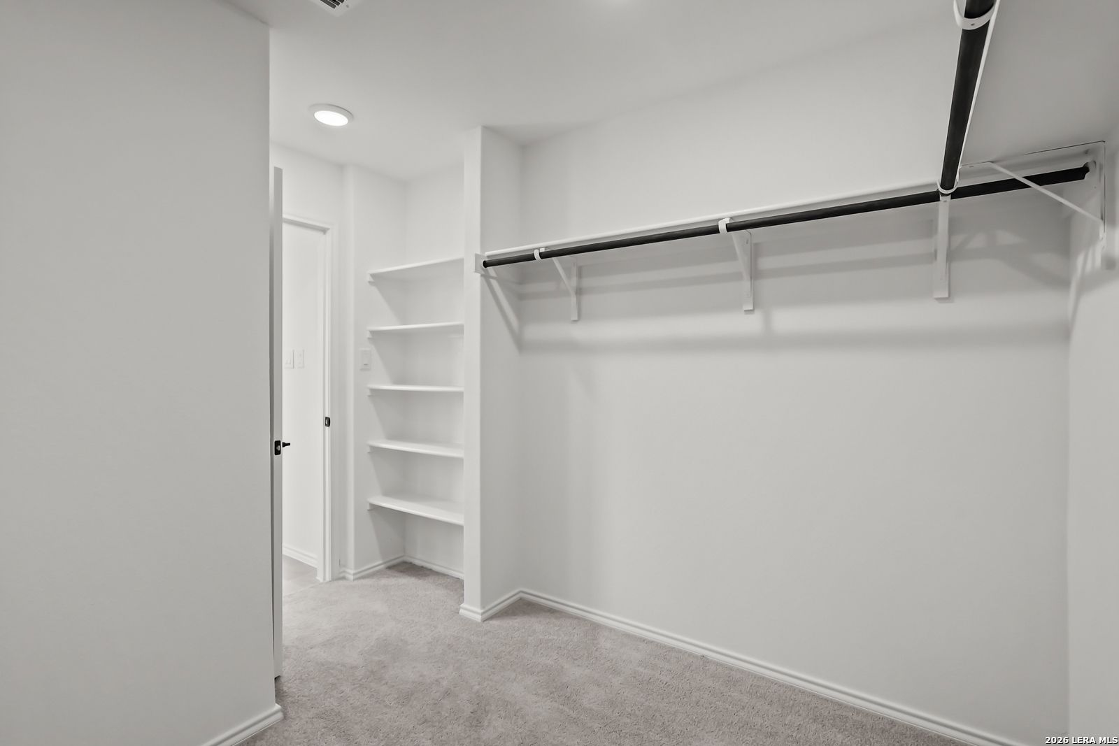 Walk-in closet with built-in shelving and hanging rod in The Florence B floor plan at Meadows at Oak Creek, San Antonio.