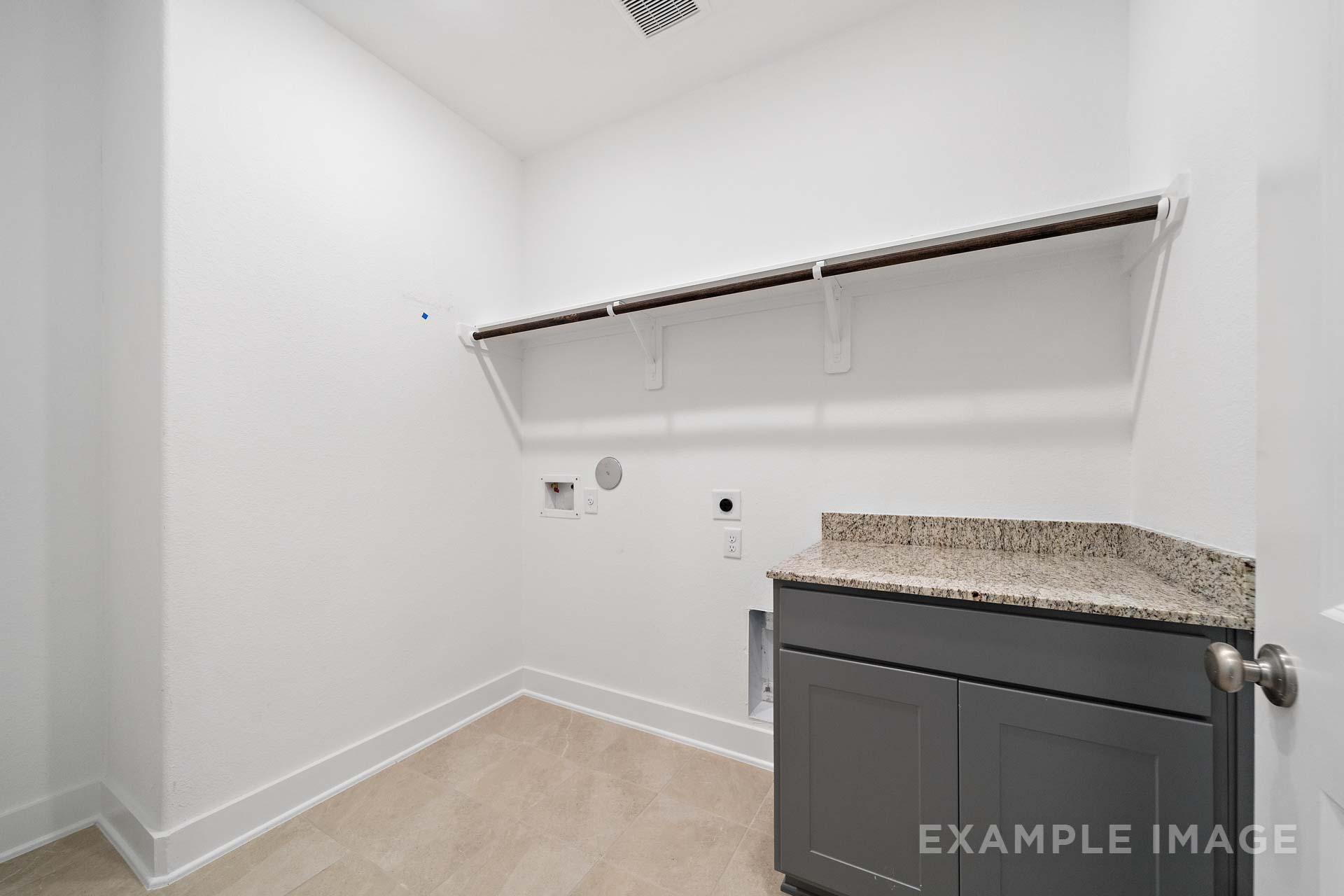 Spacious laundry room in The Diana C featuring granite countertop, gray cabinets, wooden hanging rod, and utility sink