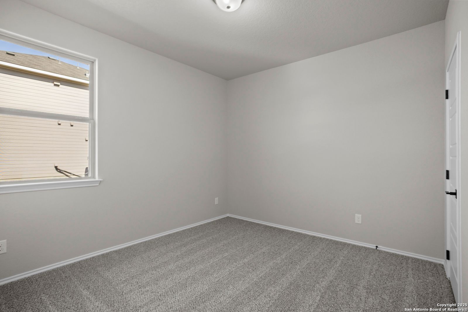 Bright secondary bedroom with light gray walls, beige carpet, large window in The Daphne H by Davidson Homes, Seguin, Texas