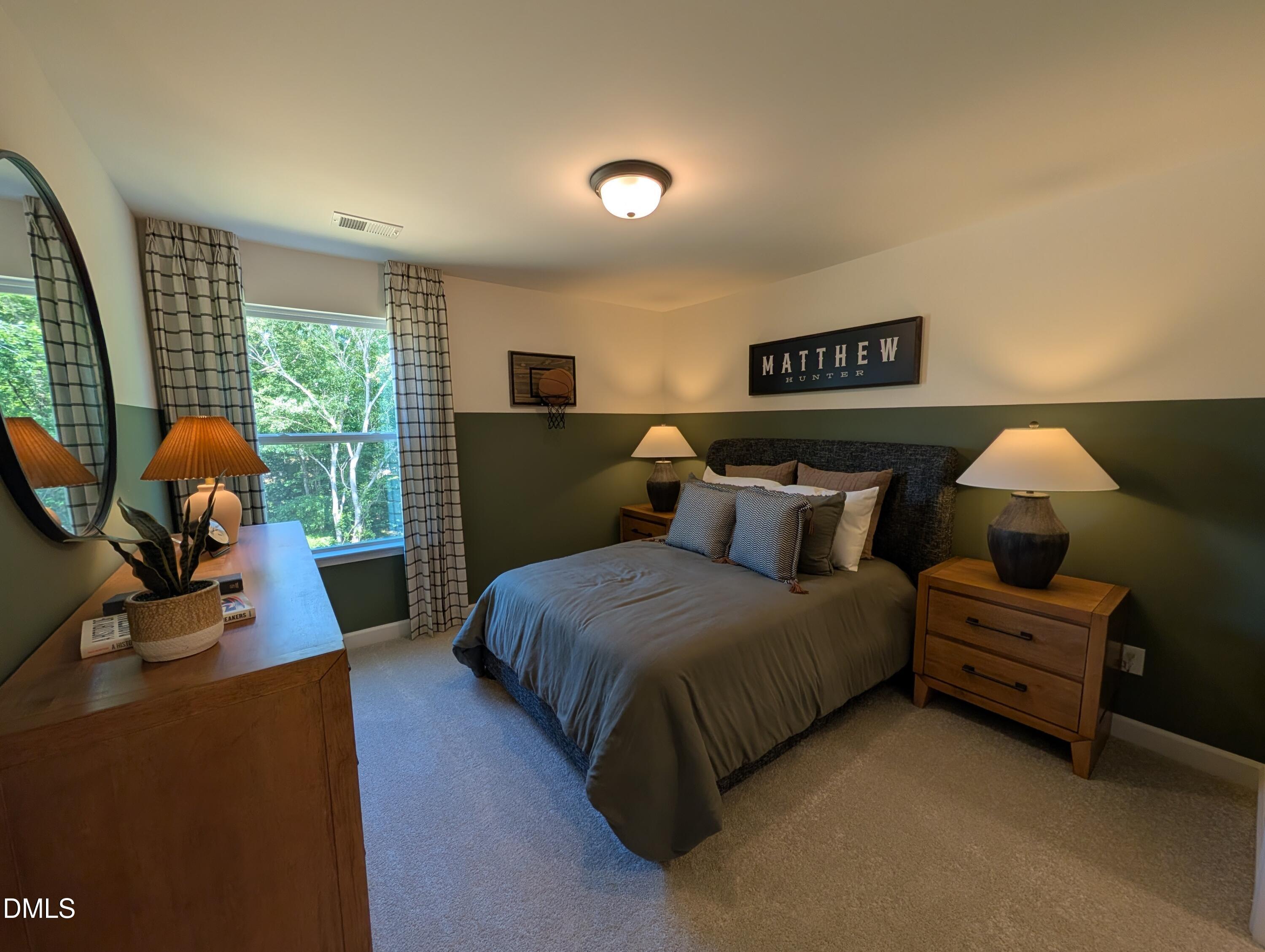 Cozy bedroom with green accent wall in The Aspen B floor plan at Wendell Ridge, Wendell, North Carolina.