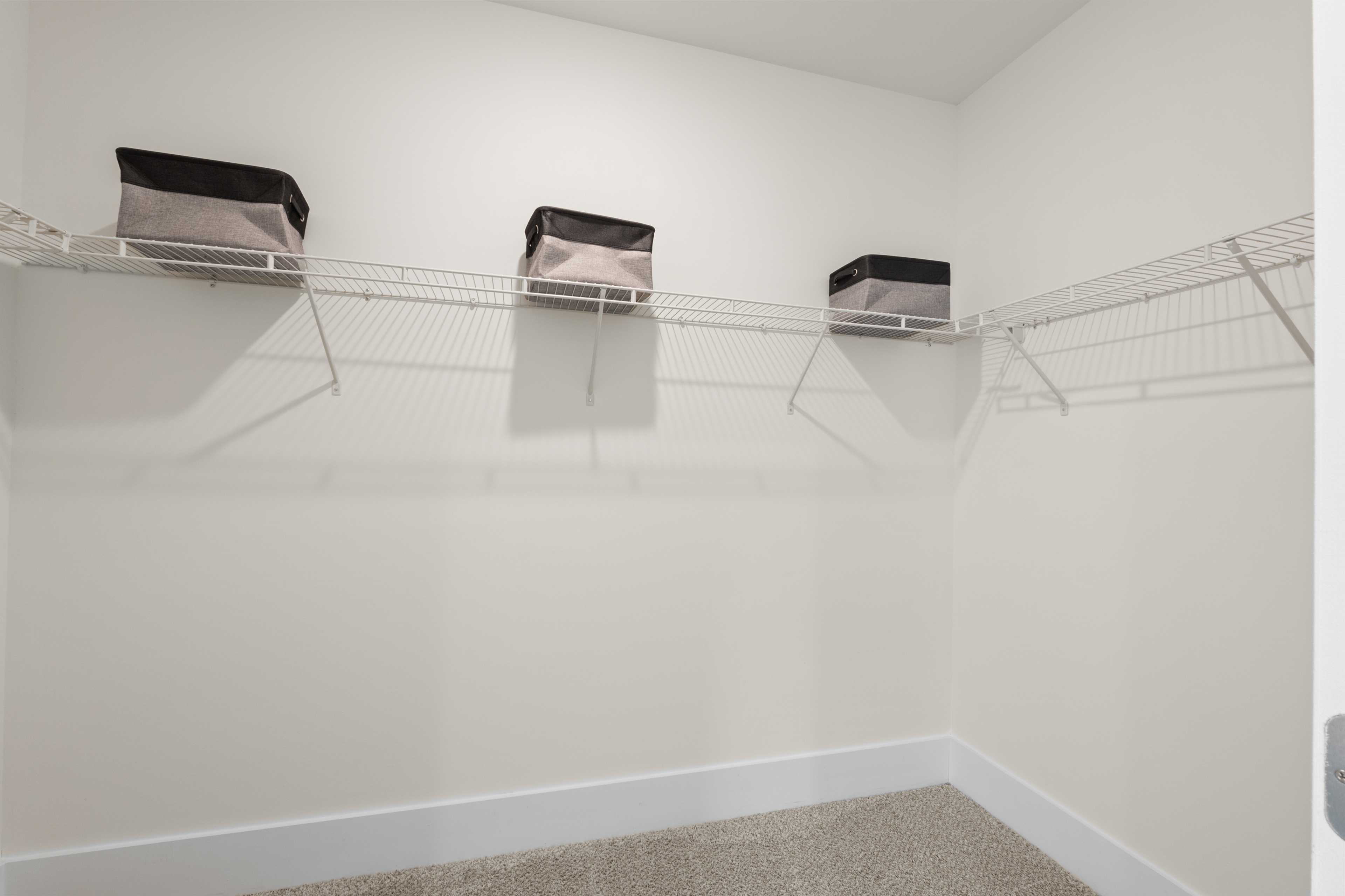 Spacious walk-in closet at Ivy Hills in Toney, Alabama with wire shelving, hanging rods, and gray storage bins