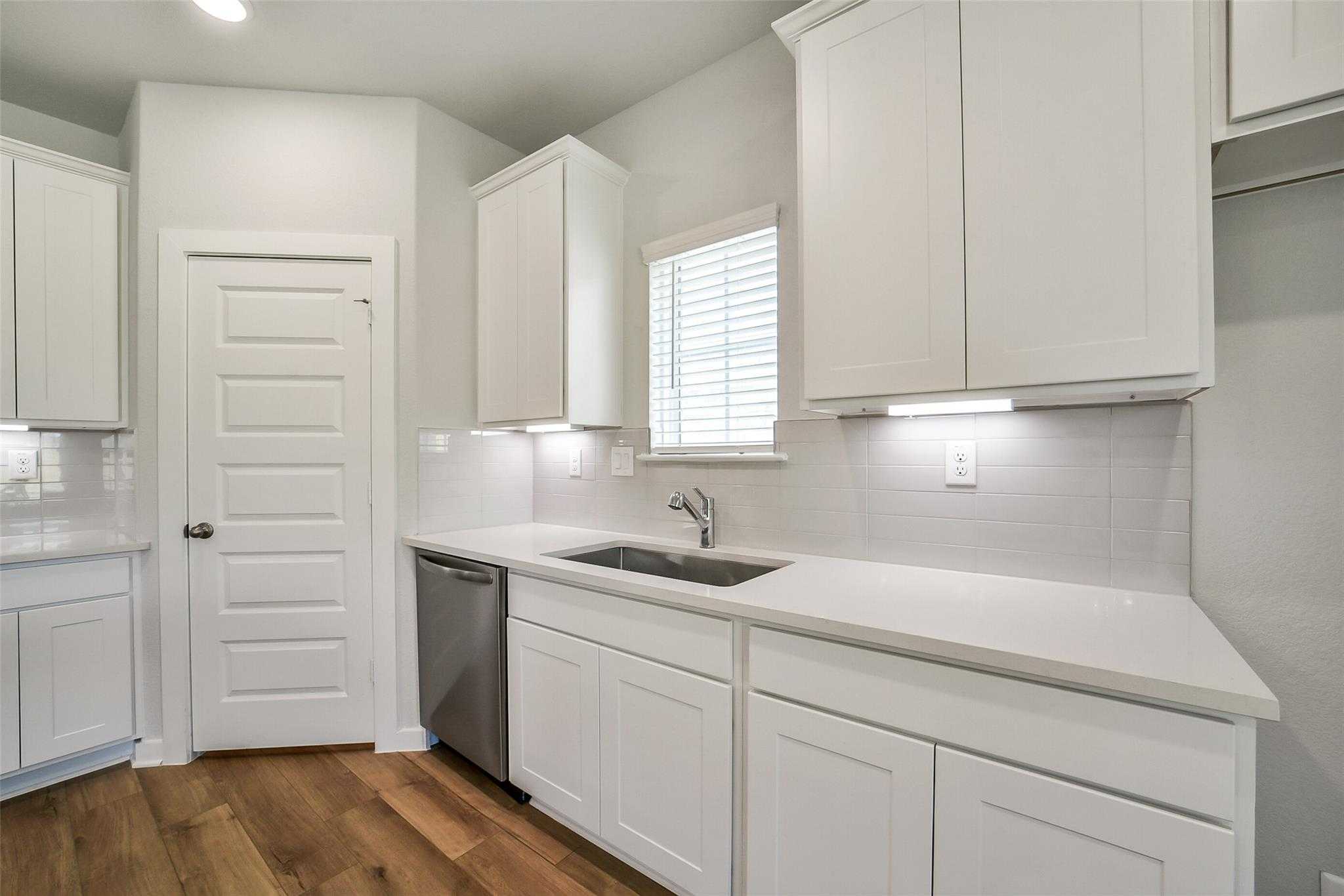 Bright white kitchen with quartz counters, subway tile backsplash, stainless sink in Davidson Homes The Trinity F, Magnolia, Texas