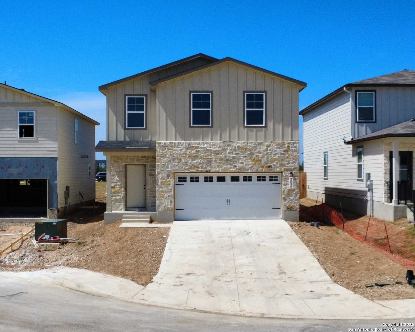 Modern two-story beige home with stone facade, double garage, and driveway in Applewhite Meadows, San Antonio