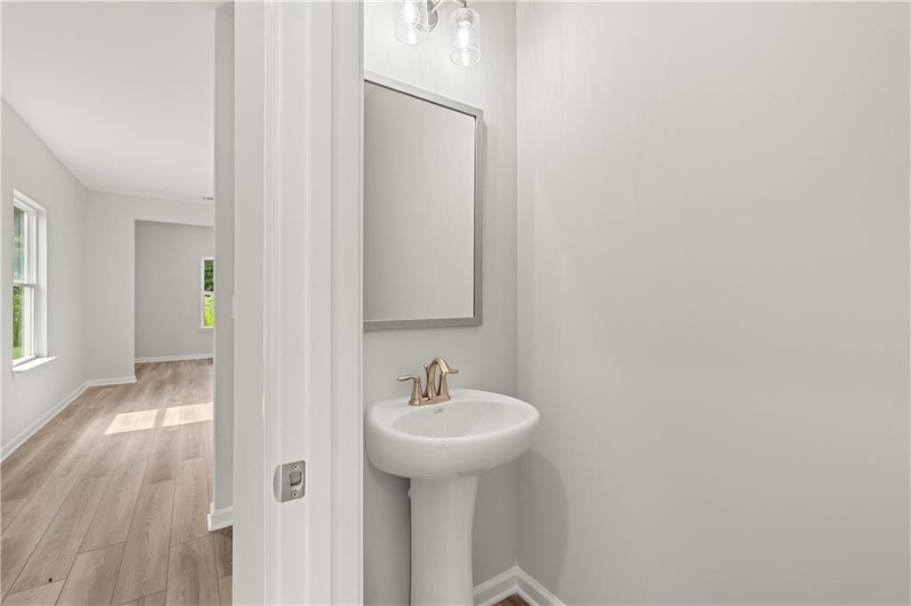 Modern powder room with pedestal sink and mirror in The Russell A floor plan at Cedar Farms in Winder, Georgia.