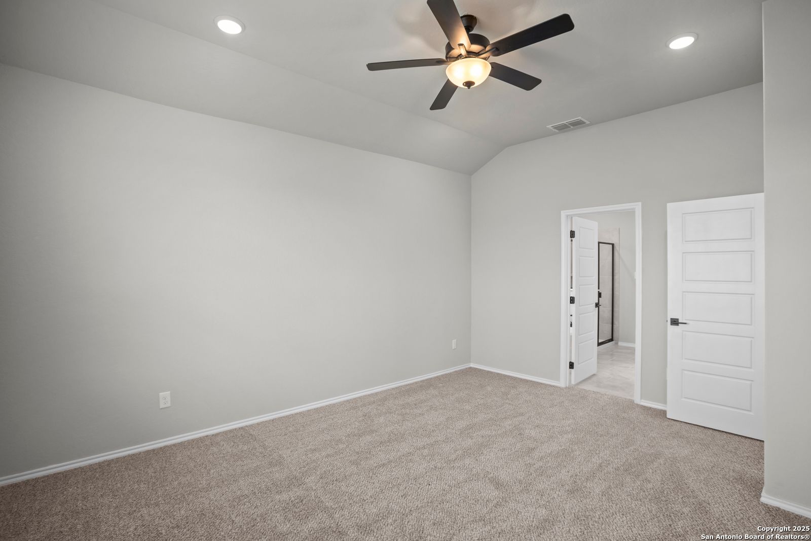 Spacious bedroom with beige carpet, ceiling fan, recessed lights, and white en-suite door in Davidson Homes The Sequoia A, Converse, Texas