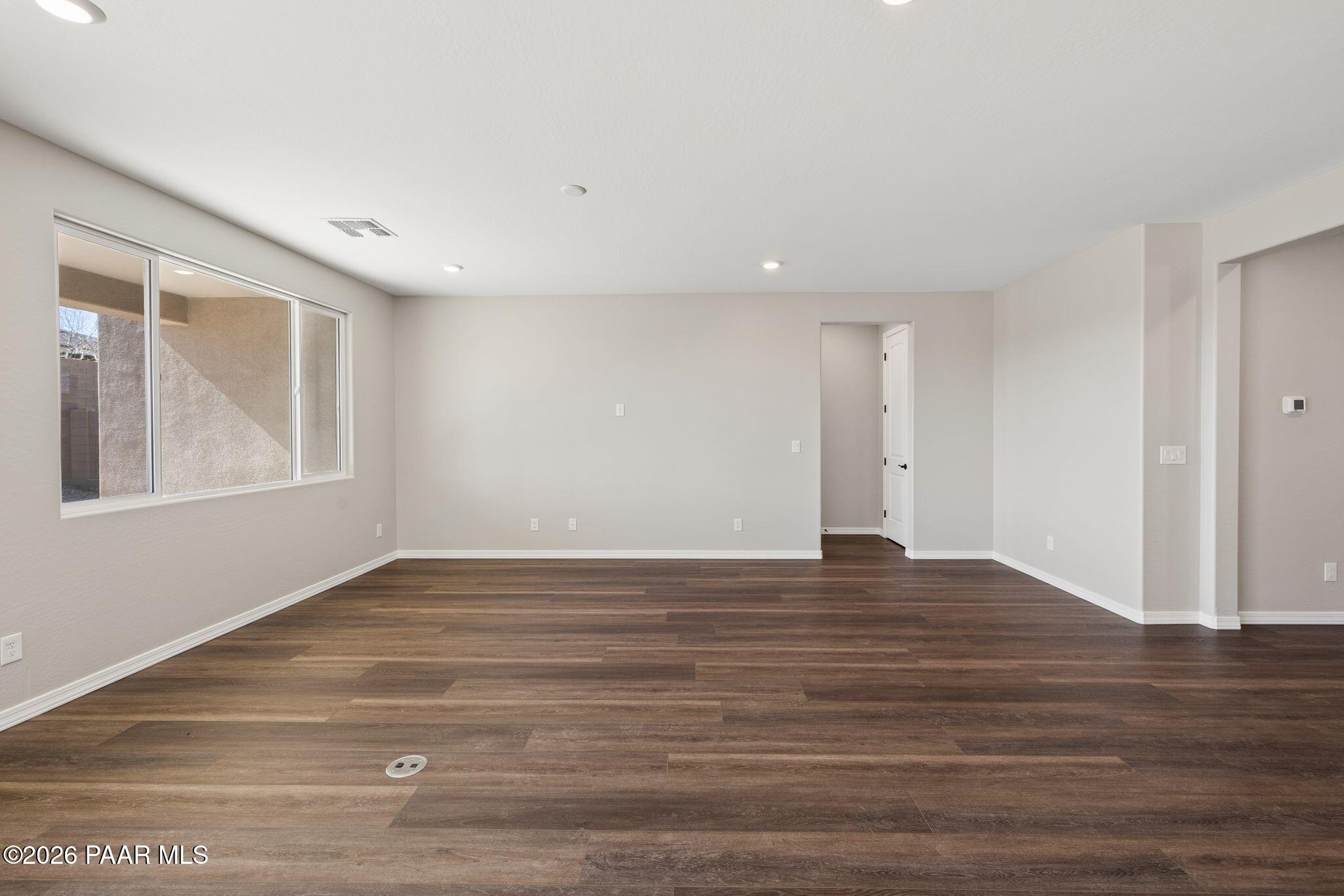 Spacious empty living room with beige walls, large windows, hardwood floors in Durango II B by Davidson Homes, Prescott AZ