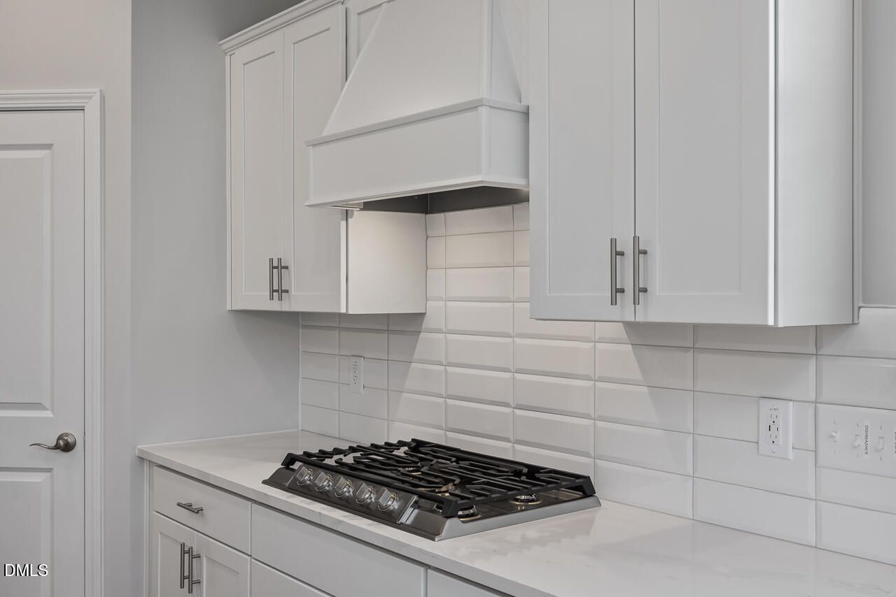 Modern kitchen with white cabinets, subway tile backsplash, and gas cooktop in The Ashport L at Sage on North Main.
