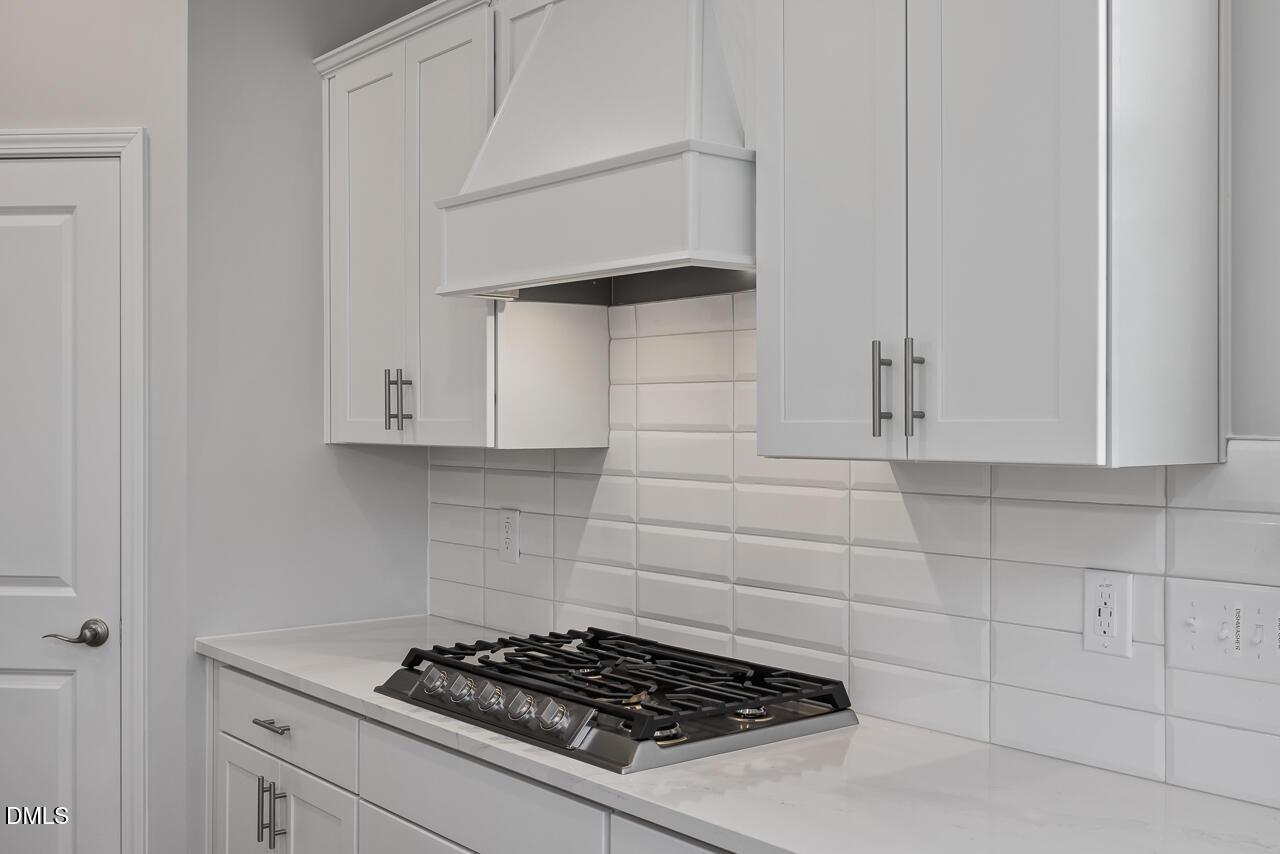 Modern kitchen with white cabinets, subway tile backsplash, and gas cooktop in The Ashport L at Sage on North Main.
