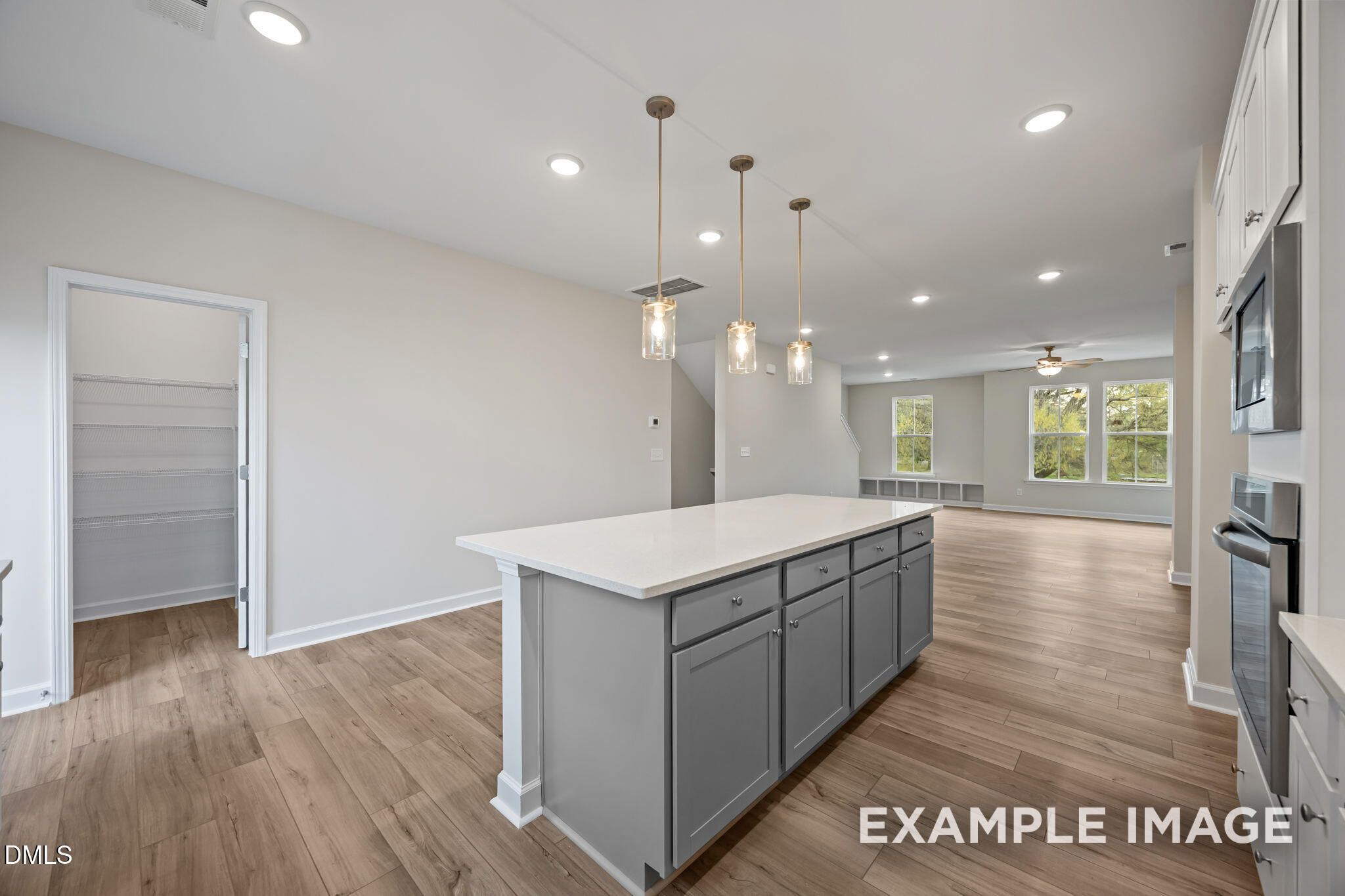 Modern open-concept kitchen with white quartz island, gray cabinets, pendant lights, and stainless appliances in The Avery, Knightdale, NC
