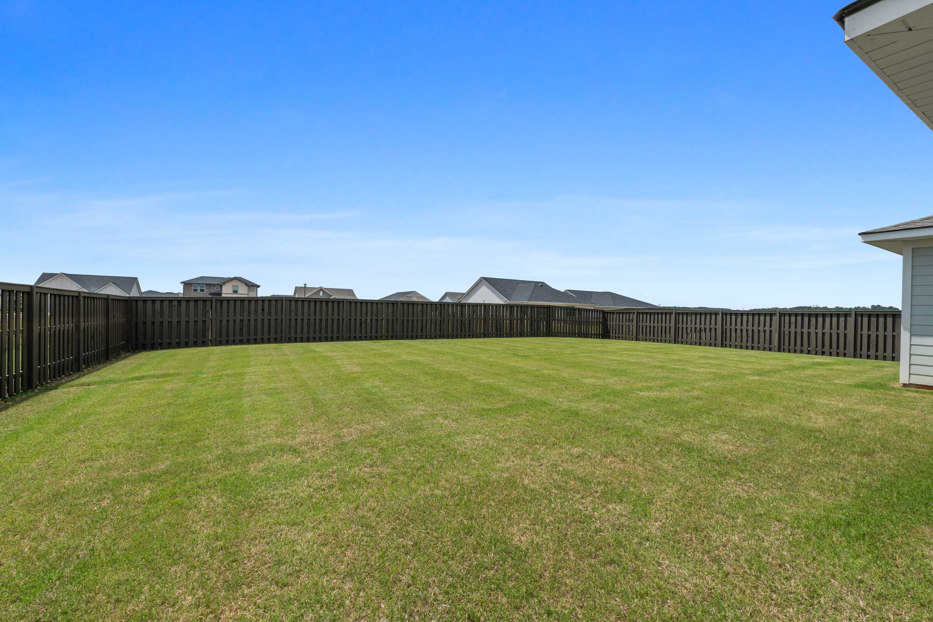Spacious fenced backyard with lush green lawn at The Meadows at Hampton Cove in Owens Cross Roads, Alabama