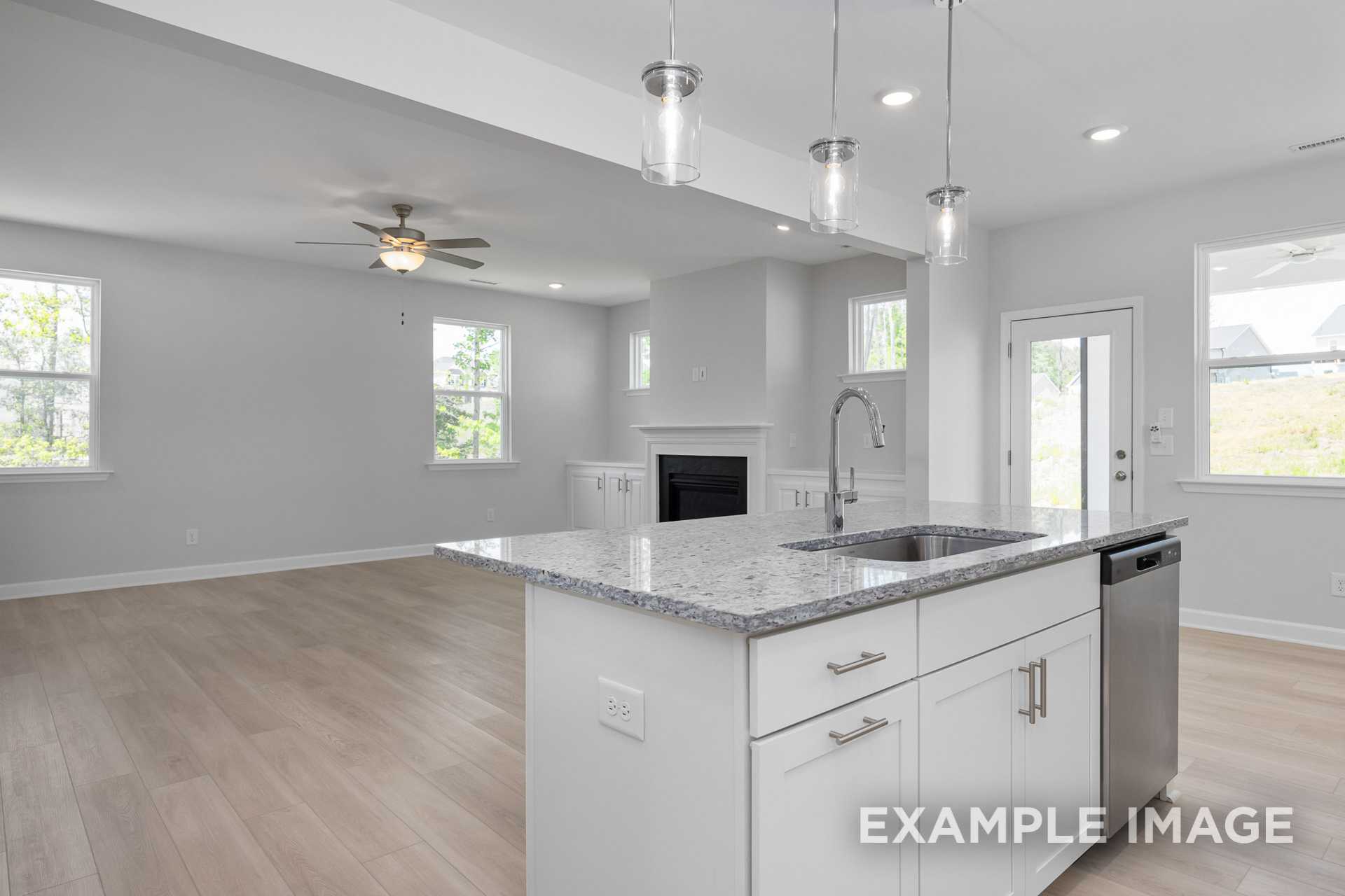 Open-concept kitchen in The Gavin C by Davidson Homes with granite island, white cabinets, pendant lights, and adjacent fireplace