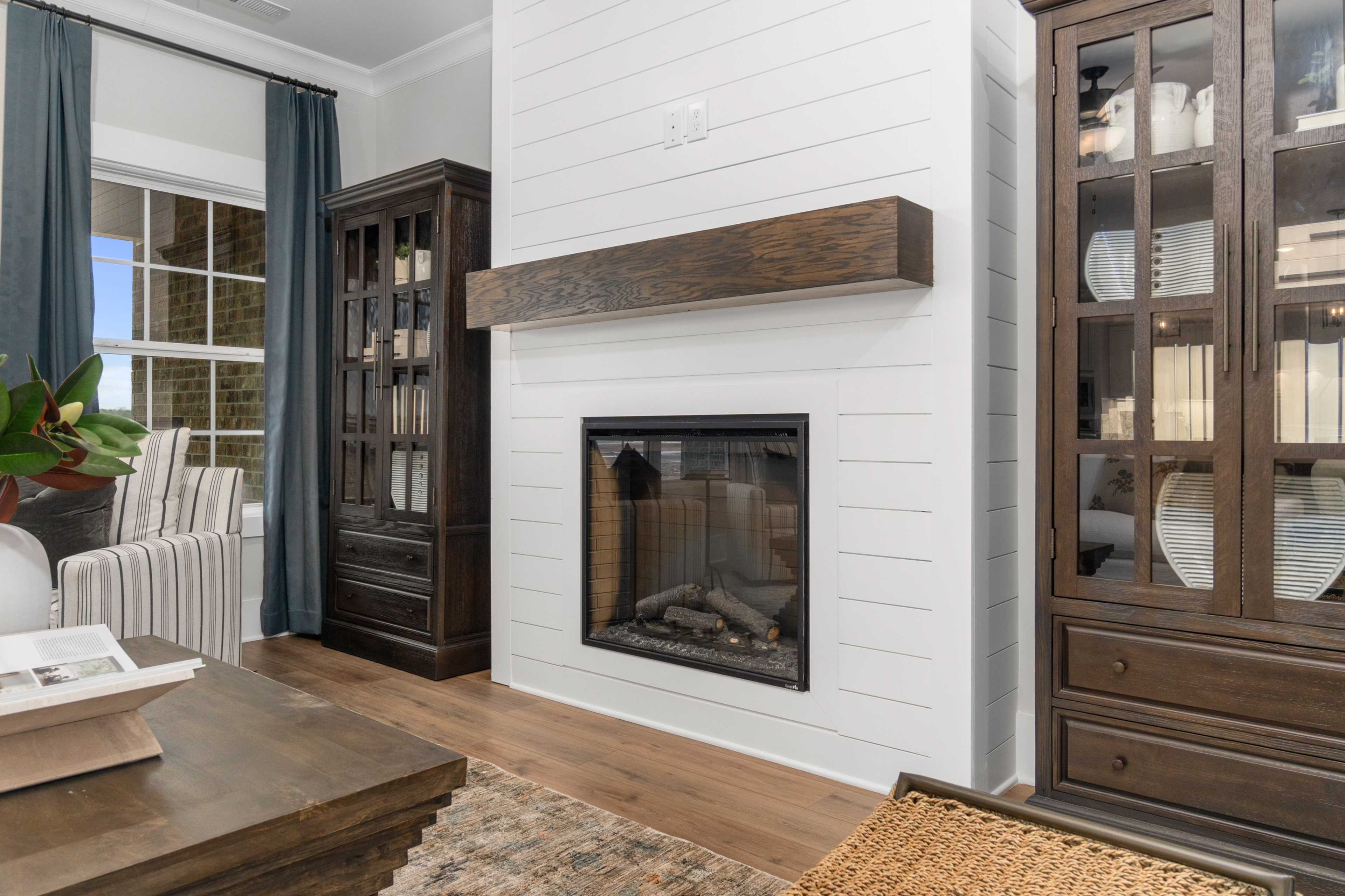 Cozy living room at Kendall Farms in Toney AL with gas fireplace, shiplap walls, wooden bookshelves, hardwood floors