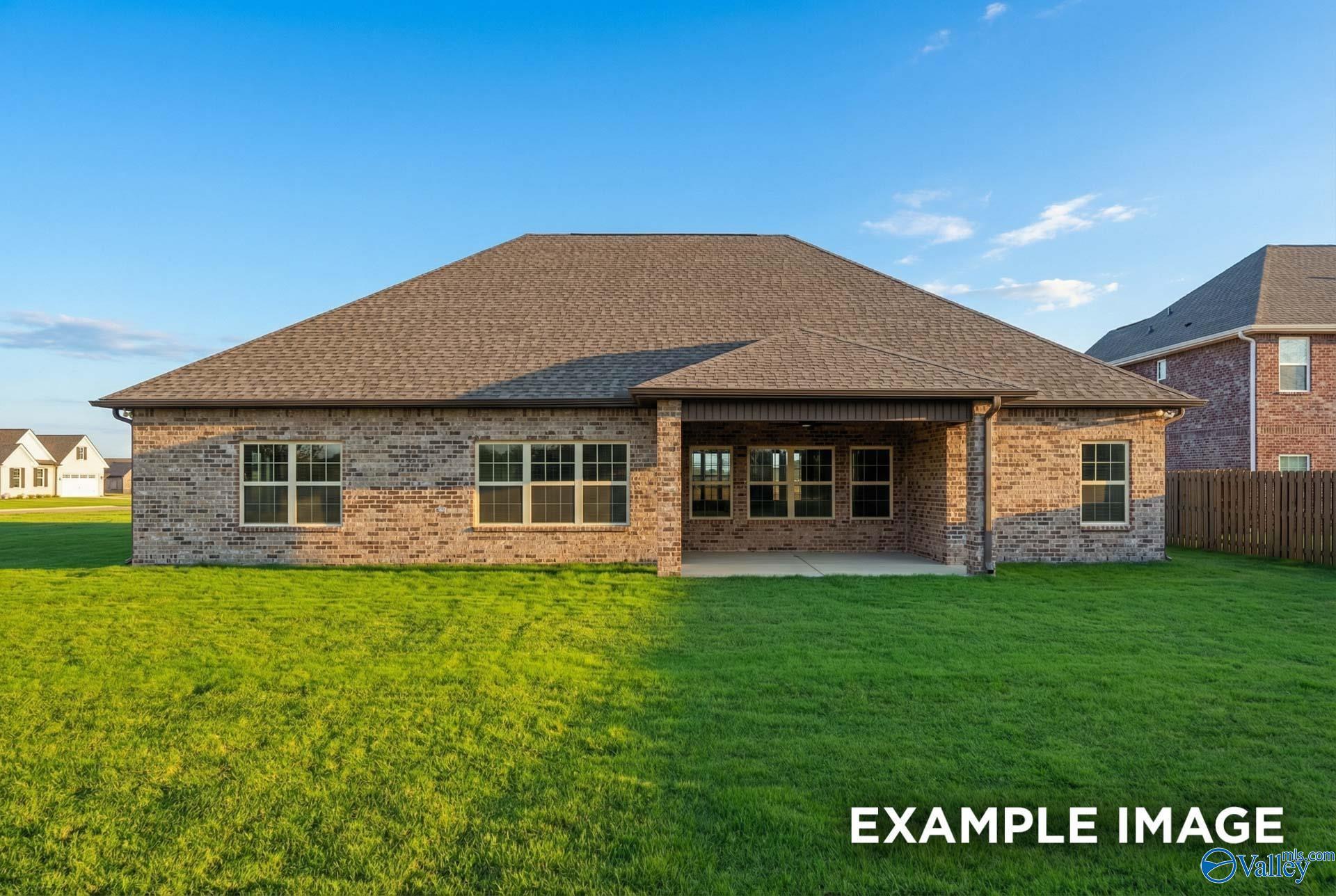 Brick 1.5-story home with covered patio, large windows, and lush green yard in Hollon Meadow, The Finleigh by Davidson Homes, Decatur AL
