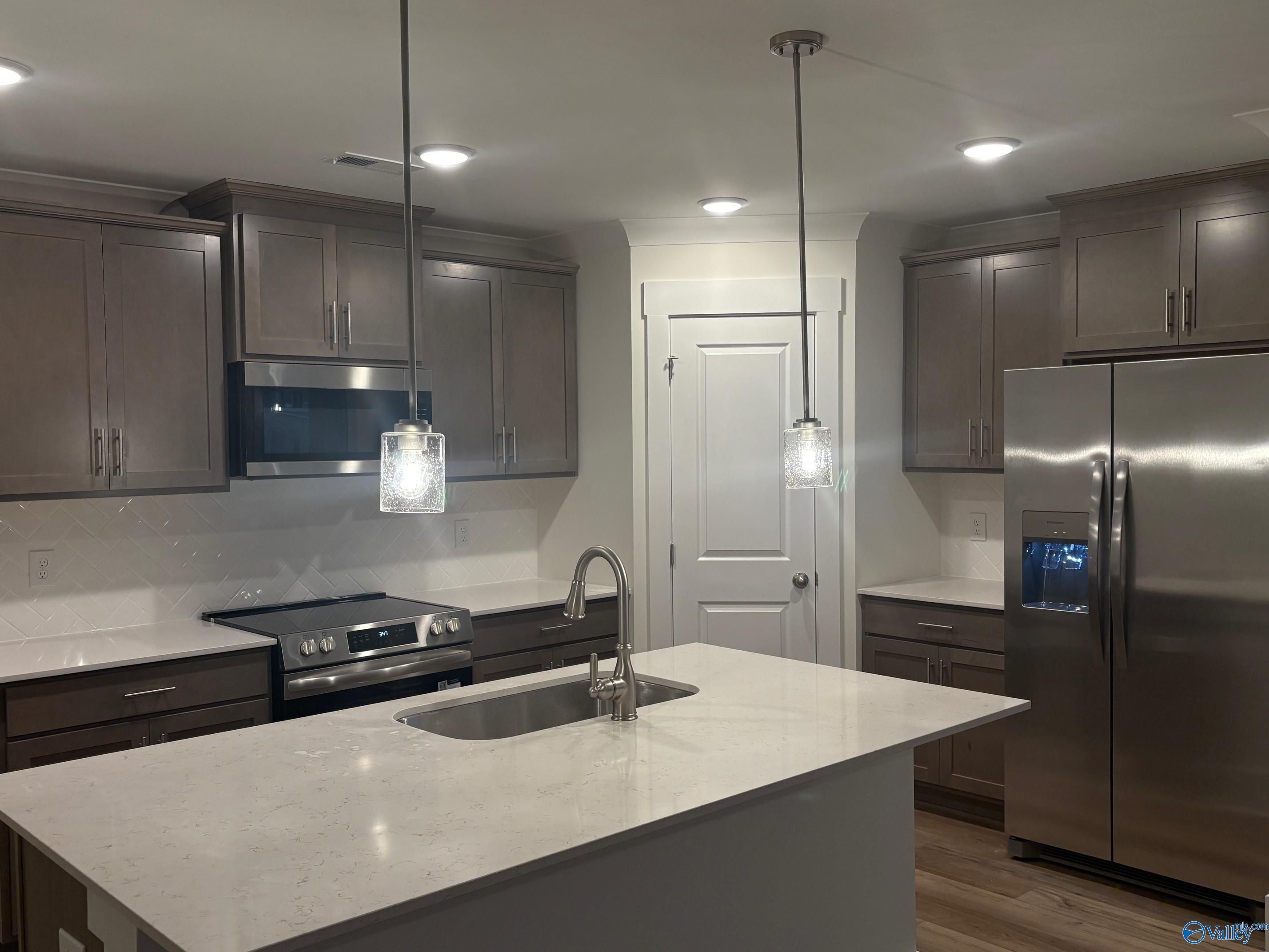 Modern kitchen with shaker cabinets, quartz countertops, stainless appliances and island in The Daphne C, Arab, Alabama