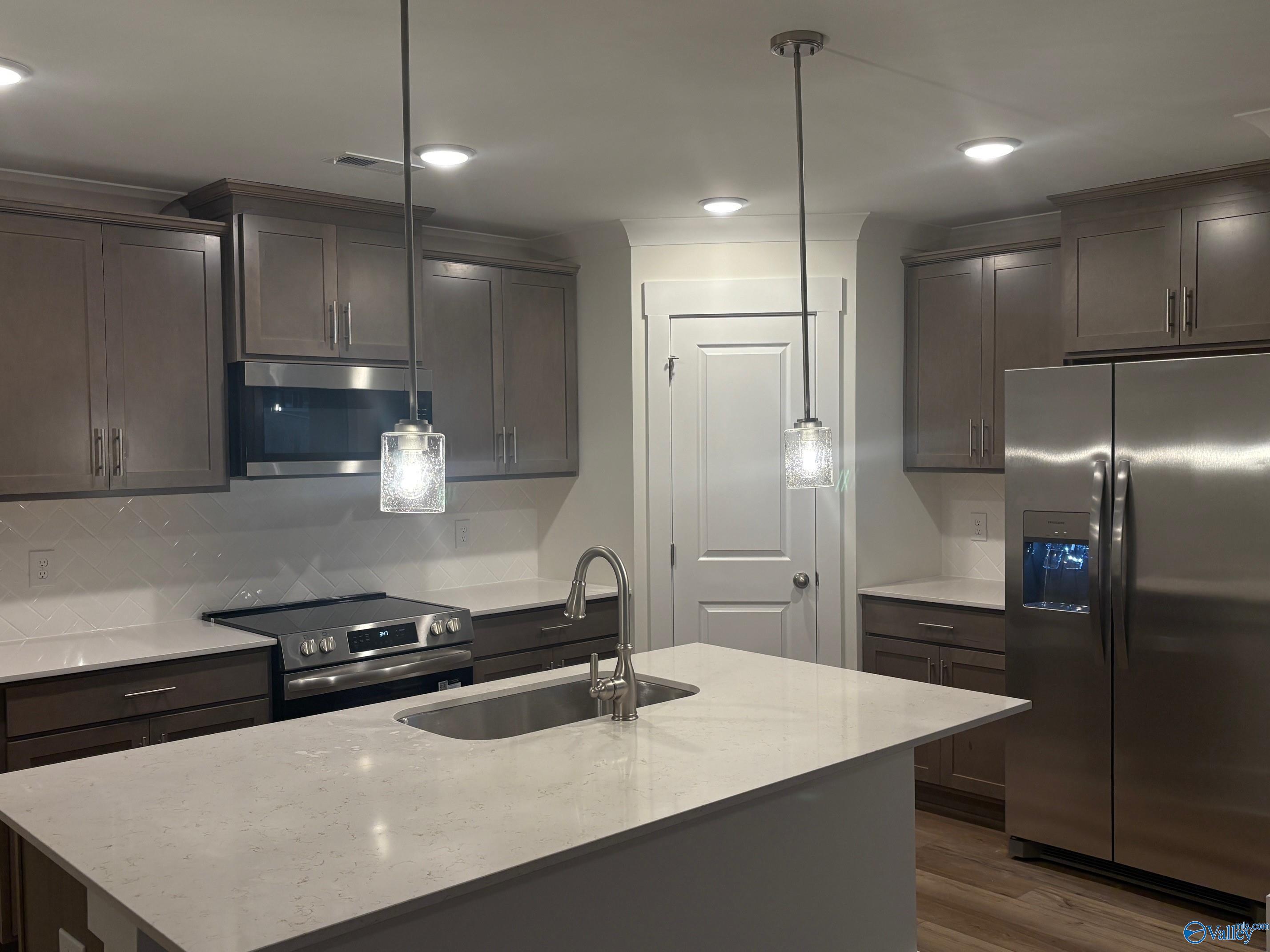 Modern shaker kitchen with quartz island, stainless fridge and range in Davidson Homes The Daphne C, Arab, Alabama