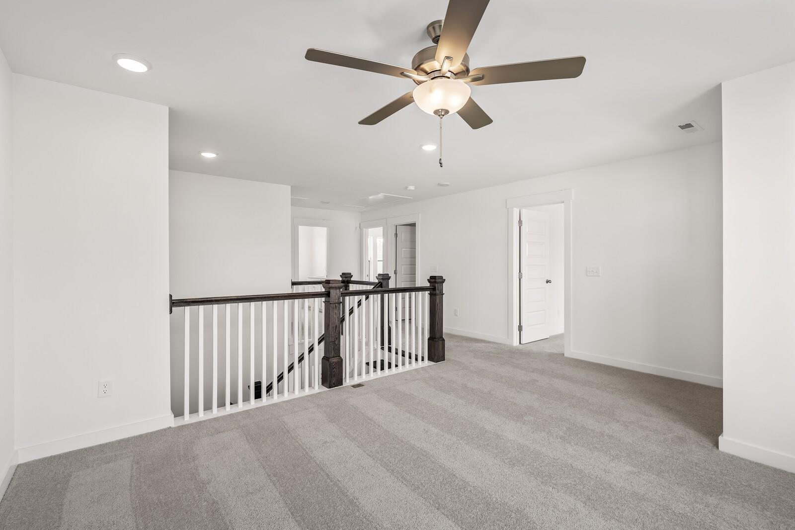 Spacious carpeted loft area with ceiling fan in The Willow D floor plan by Davidson Homes in Mt. Juliet, Tennessee.