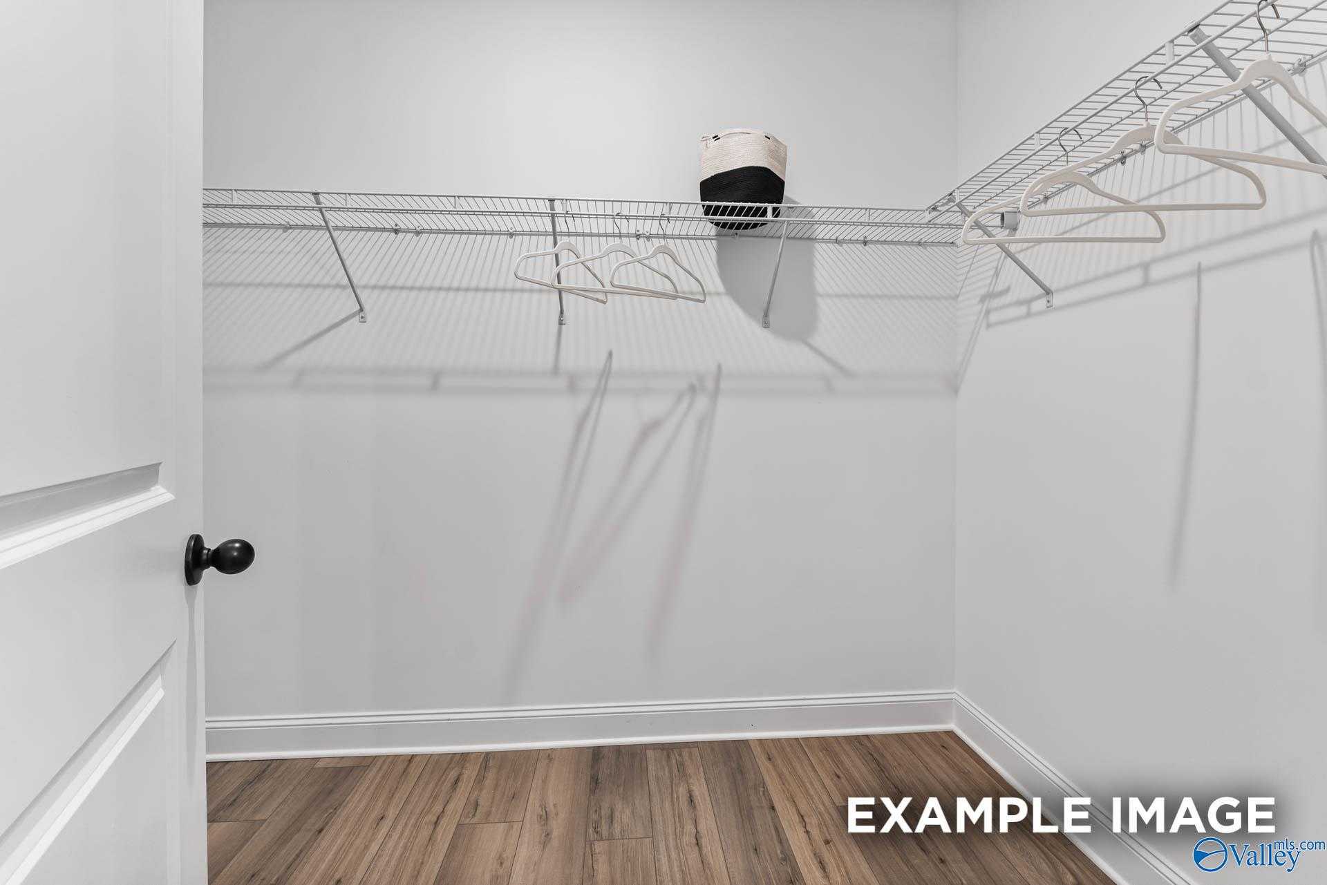 Spacious walk-in closet with wire shelving, hanging rods and hardwood floors in Davidson Homes The Franklin, Huntsville, Alabama