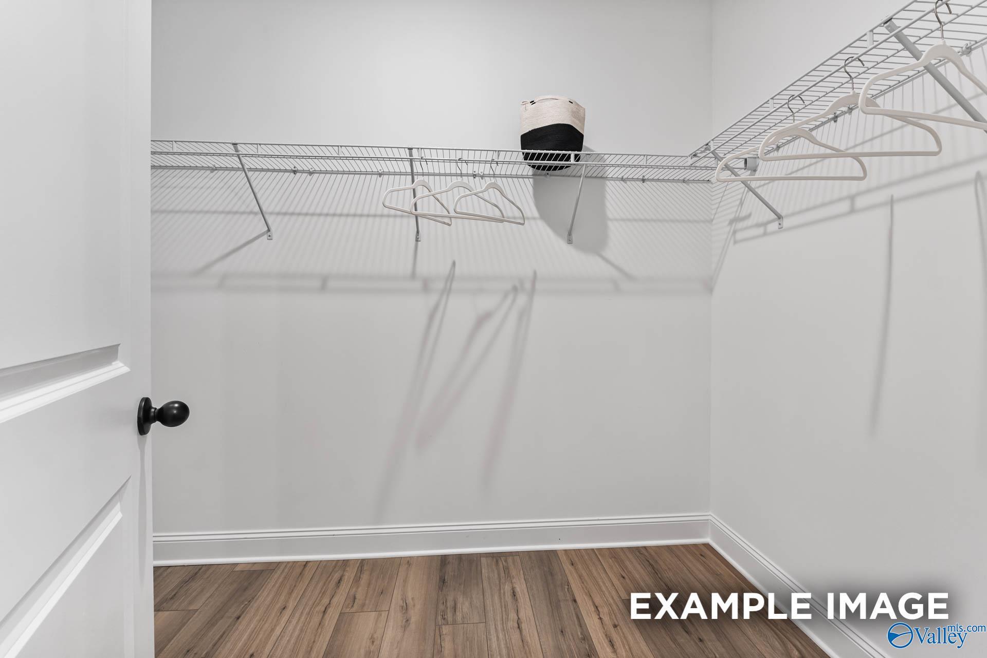 Spacious walk-in closet with wire shelving, hanging rods and hardwood floors in Davidson Homes The Franklin, Huntsville, Alabama