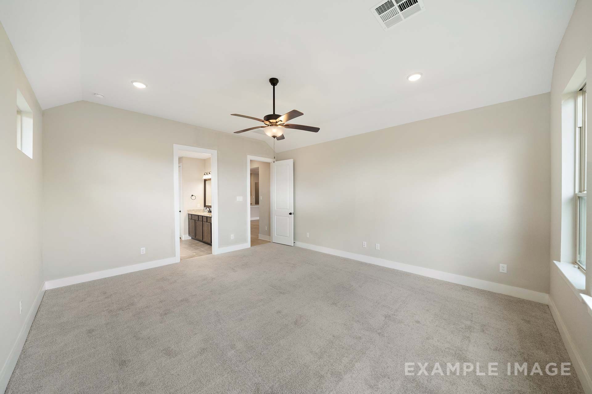 Spacious master suite on main floor of The Elizabeth by Davidson Homes featuring vaulted ceiling, ceiling fan, and carpet flooring