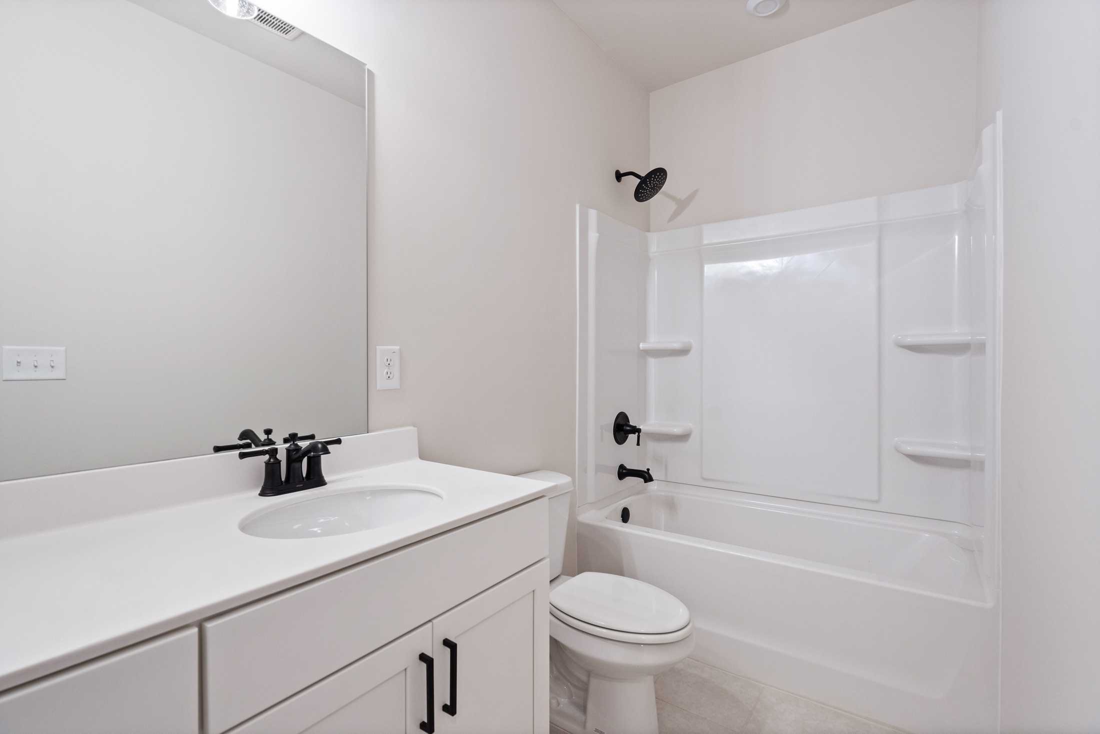 Modern secondary bathroom in The Glenwood B by Davidson Homes featuring white vanity, tub-shower combo, and black fixtures