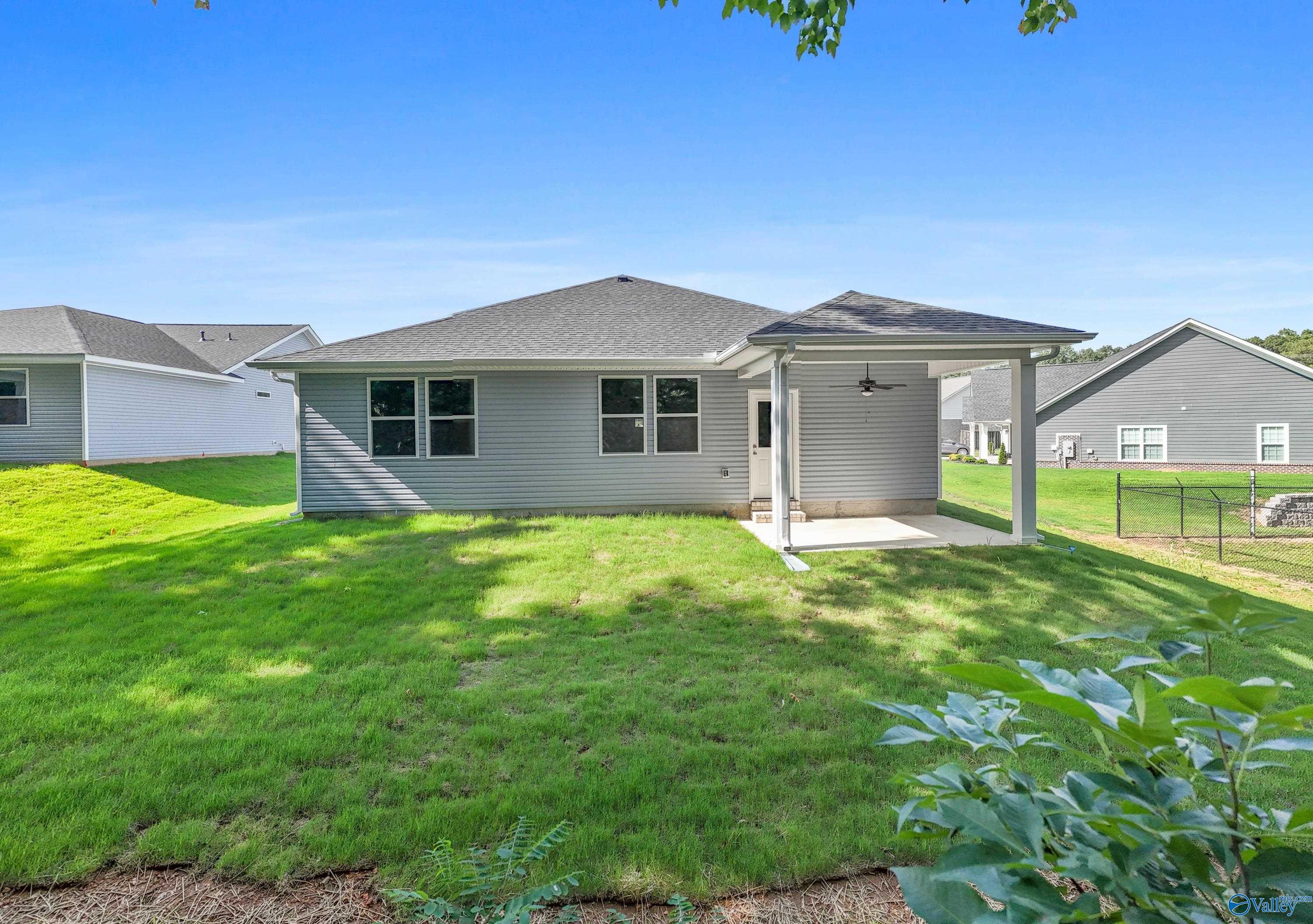 Rear view of The Polaris 3-bedroom home by Davidson Homes with covered patio, lush green yard, and fence in Bailey Park, Fayetteville, Tennessee