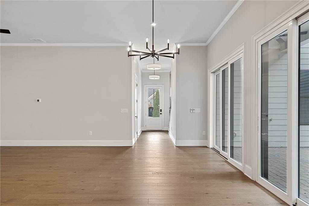 Spacious hallway with hardwood floors, modern chandelier, and sliding glass doors in Davidson Homes The Seaside B, Woodstock, GA