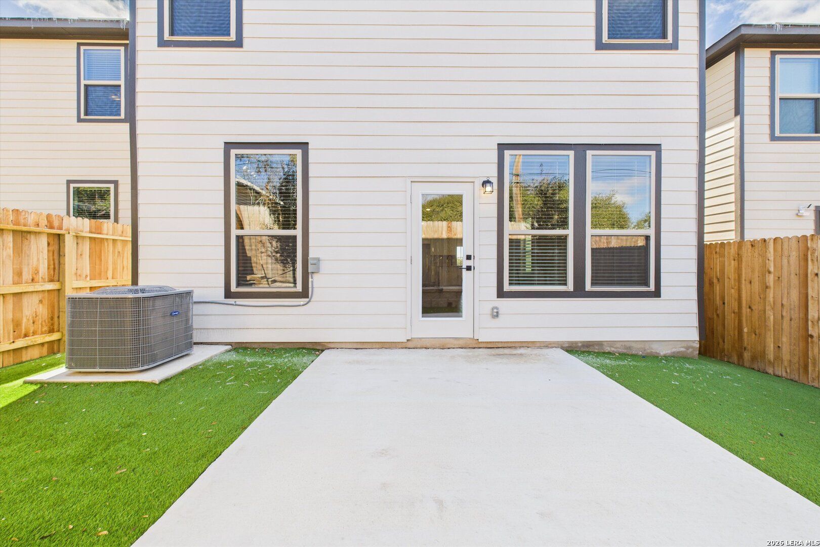 Spacious backyard patio with glass door and wooden fence in 4-bedroom The Gillian B home, Meadows at Oak Creek, San Antonio, Texas