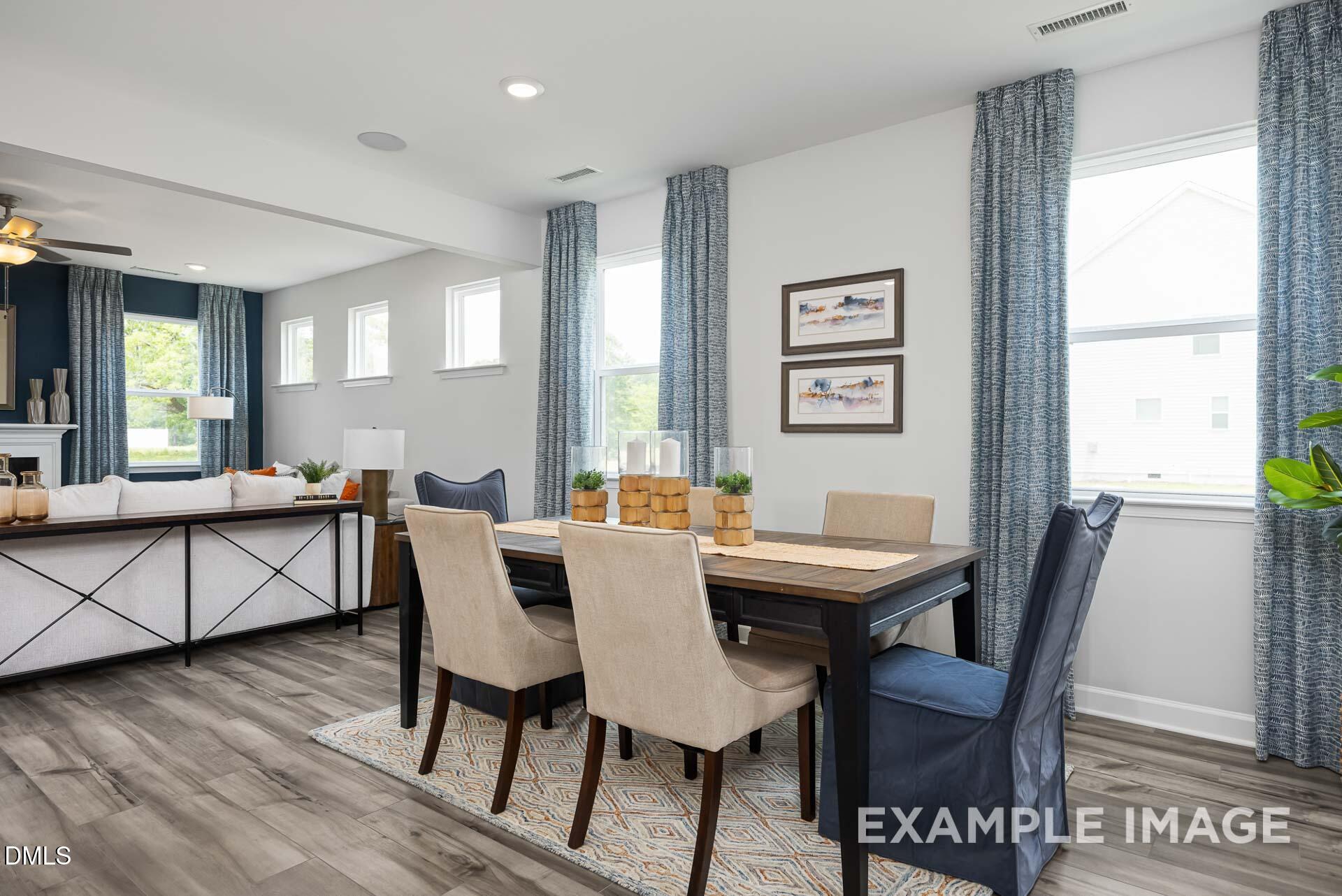Open-concept dining area with wood table and modern chairs in The Adalynn A floor plan, Woodland Crossing, Zebulon, NC.