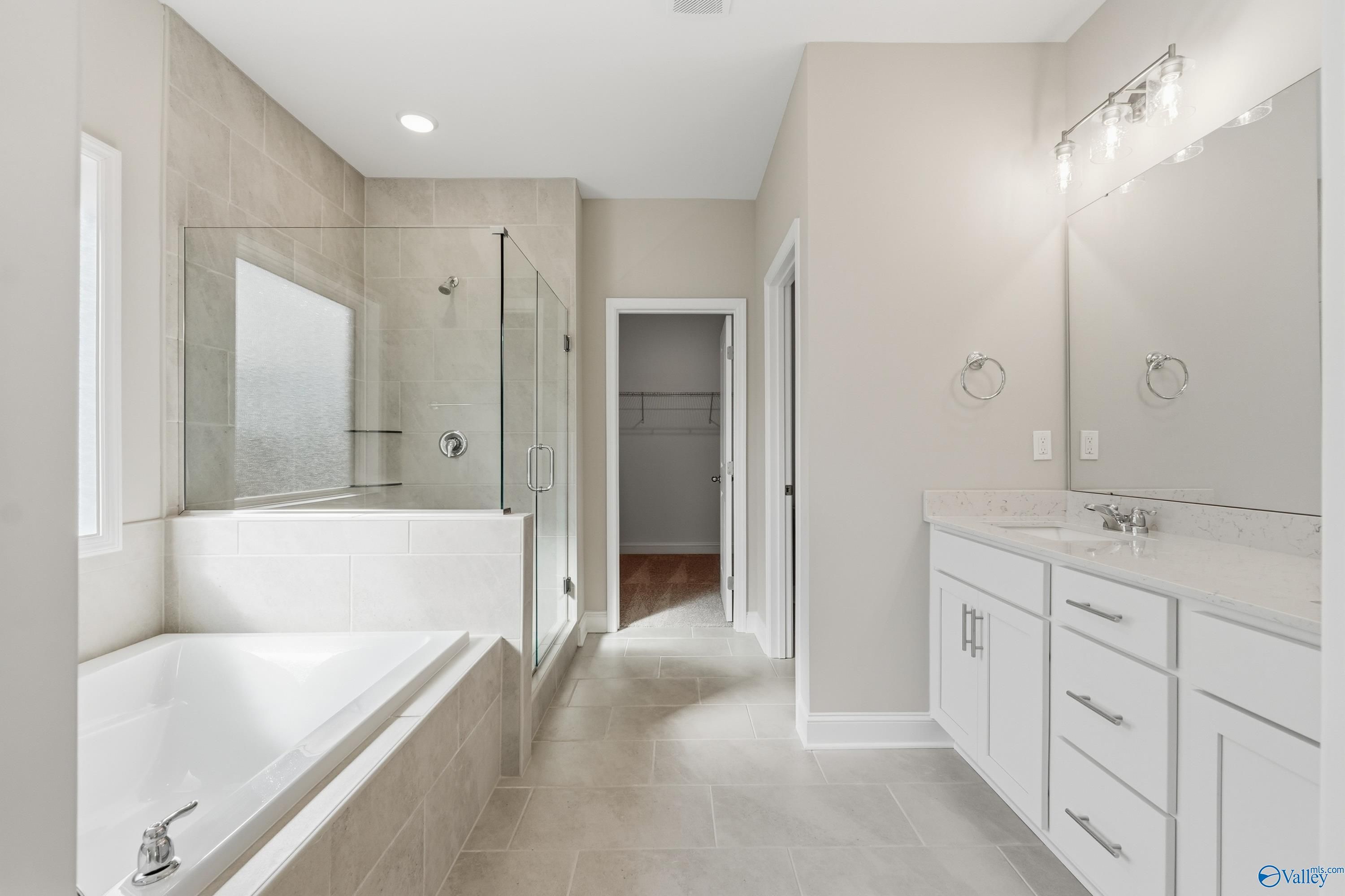 Elegant master bathroom with frameless glass shower, deep soaking tub, and double vanity in Davidson Homes The Rockford, Harvest, Alabama
