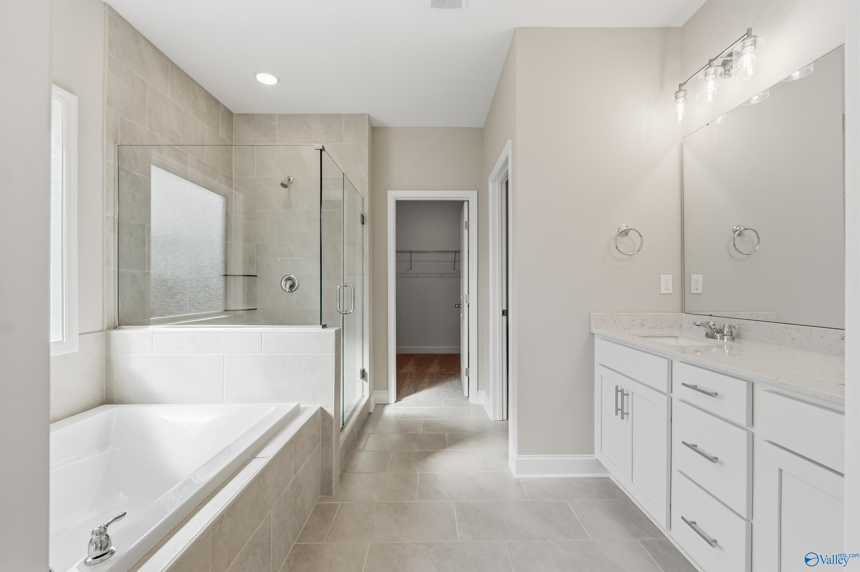 Elegant master bathroom with frameless glass shower, deep soaking tub, and double vanity in Davidson Homes The Rockford, Harvest, Alabama