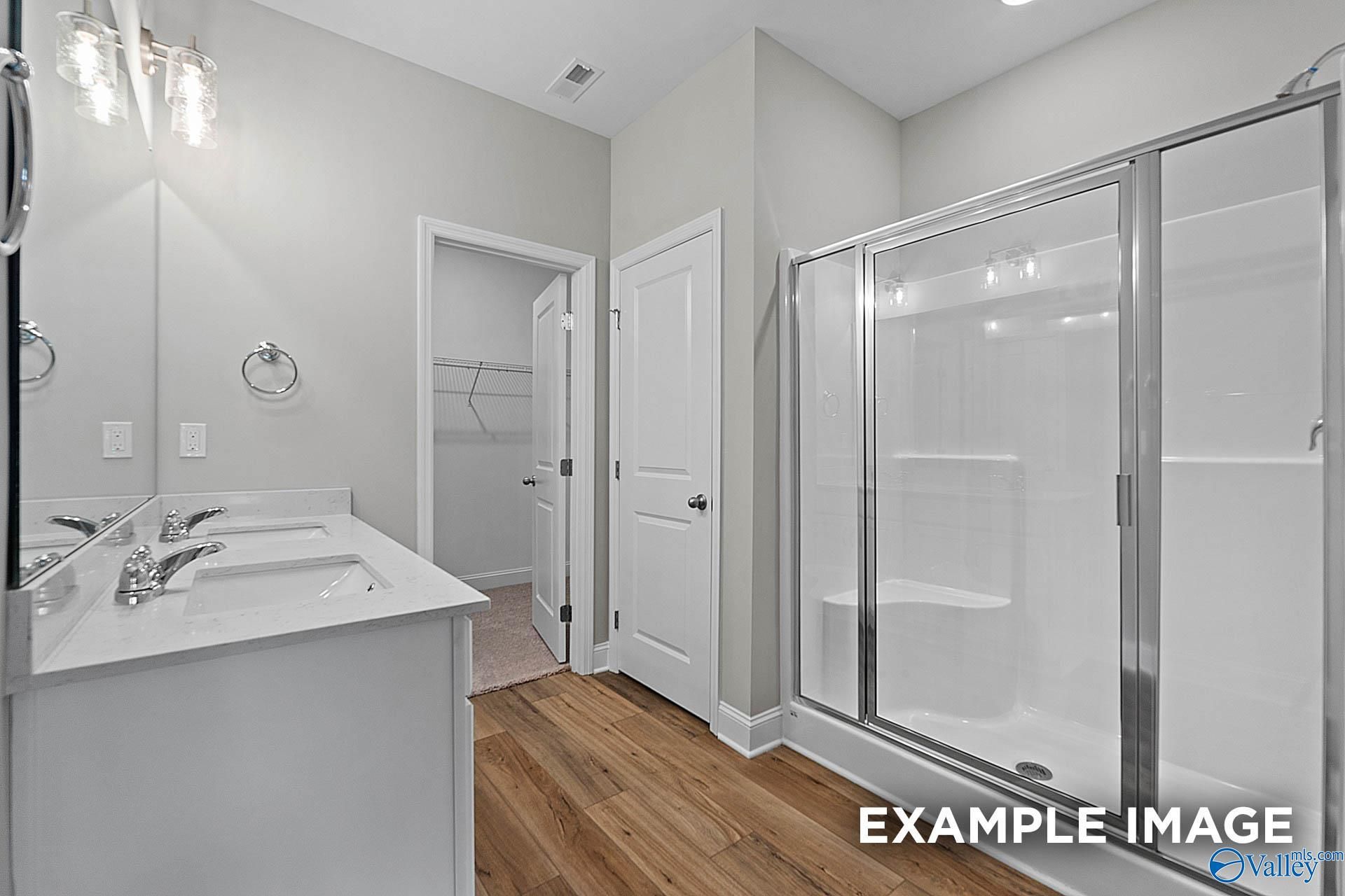 Modern master bathroom with double vanity, frameless glass shower, and closet access in Davidson Homes The Franklin E, Hazel Green, AL