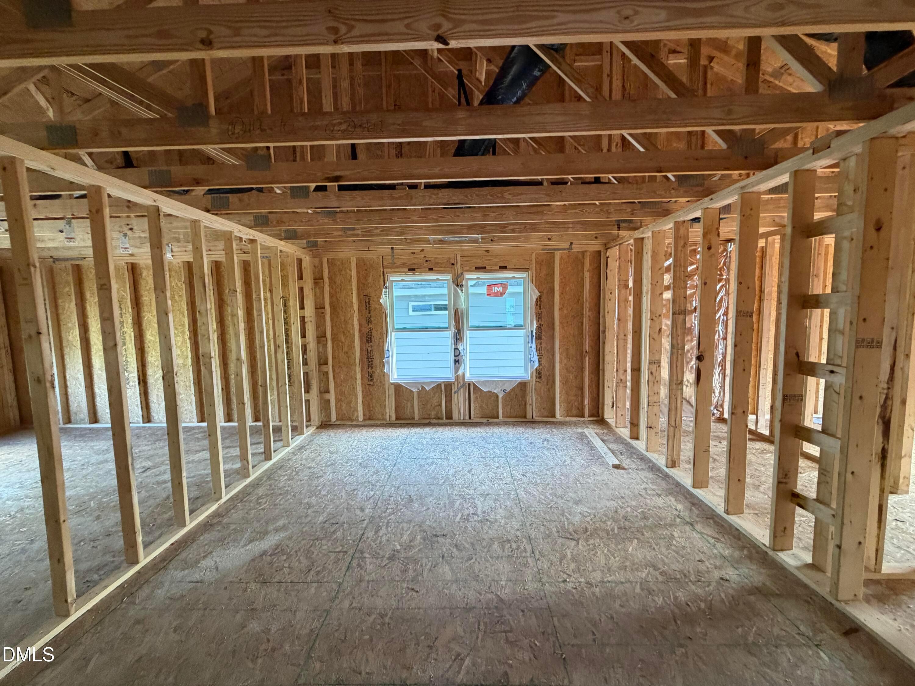 Unfinished wood-framed bonus room with windows and exposed trusses under construction in The Beech floor plan, Wendell Ridge, NC