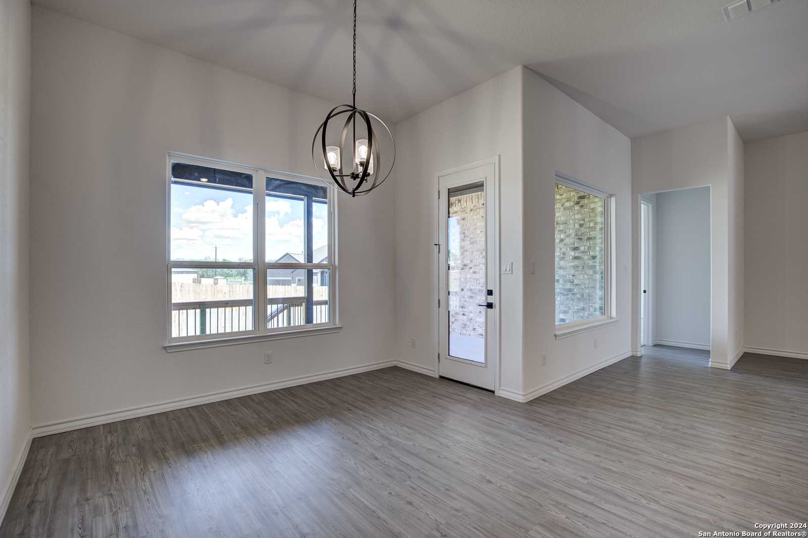 Bright dining area with vaulted ceiling, chandelier, large windows, and balcony view in The Garner B, Castroville, Texas