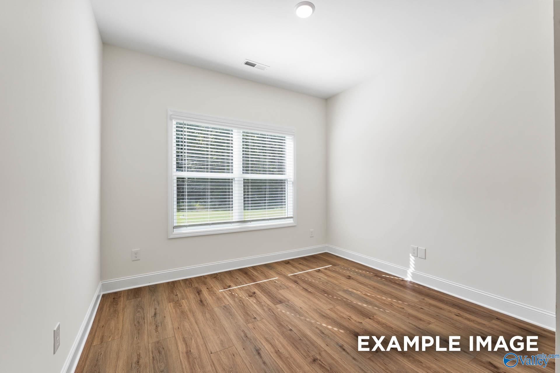 Bright secondary bedroom featuring hardwood floors, large window with blinds in Davidson Homes The Shelby A, Hazel Green, Alabama