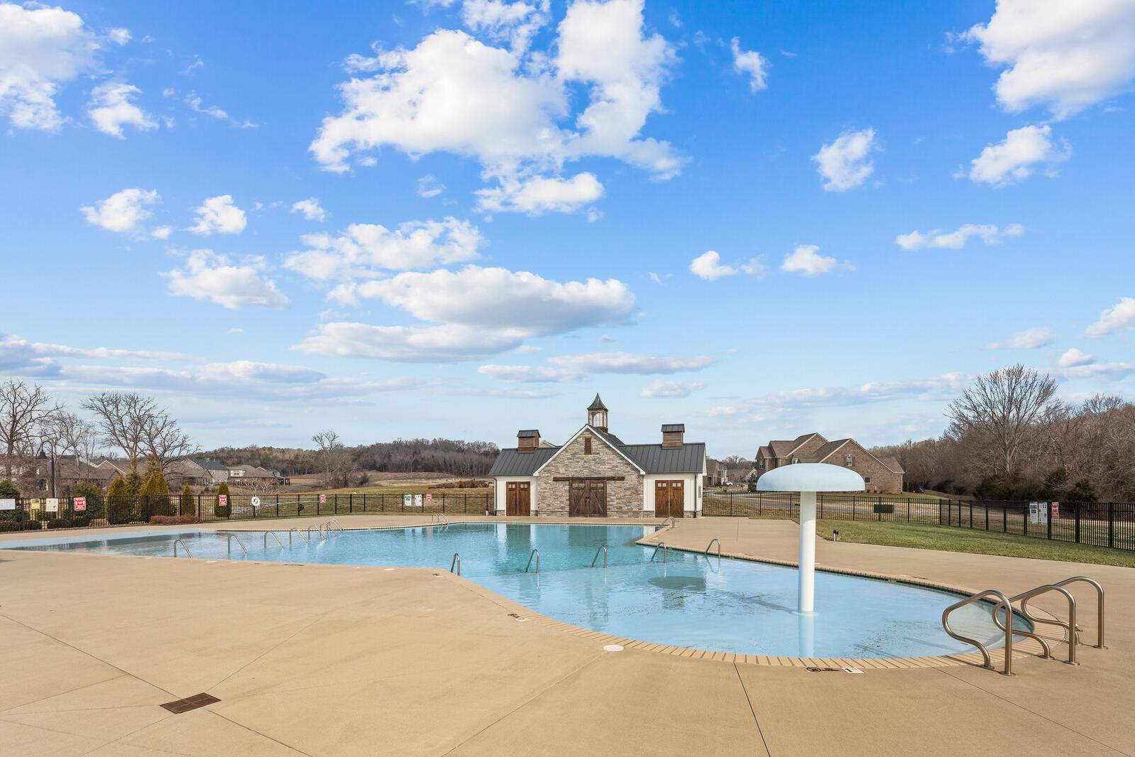 Resort-style swimming pool at Carellton in Gallatin Tennessee featuring stone clubhouse with steeple and shaded lounge deck