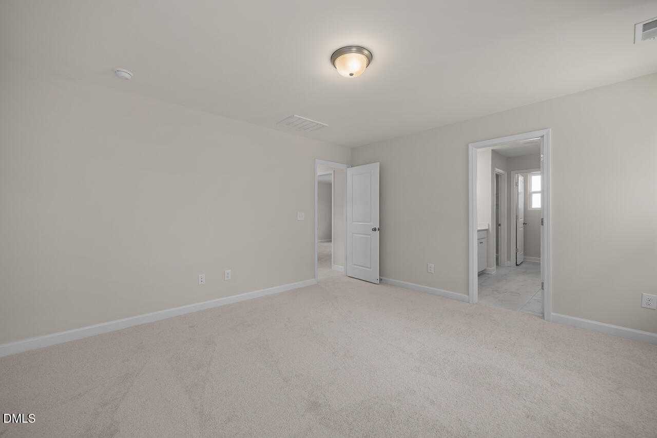 Spacious empty bedroom with en-suite bathroom access and closet door in Davidson Homes The Gavin C, Lillington, NC