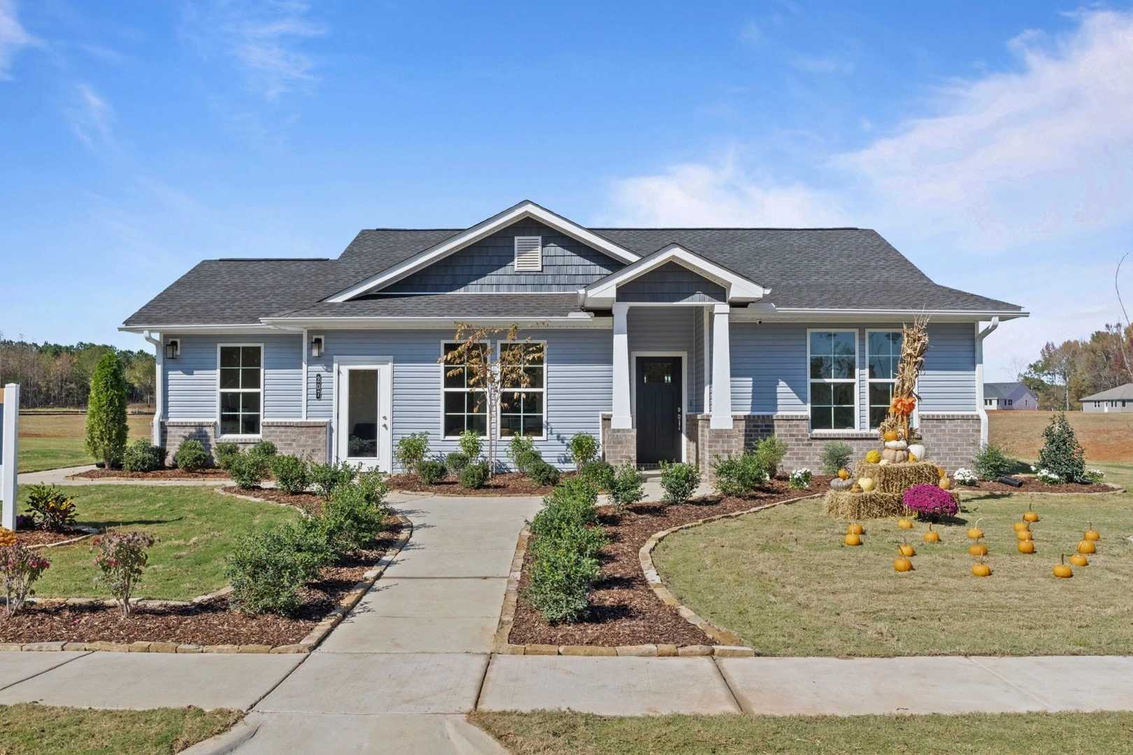 The Phoenix single-story home exterior in Perry, GA: blue siding, gabled shingle roof, landscaped yard with pathway and sign