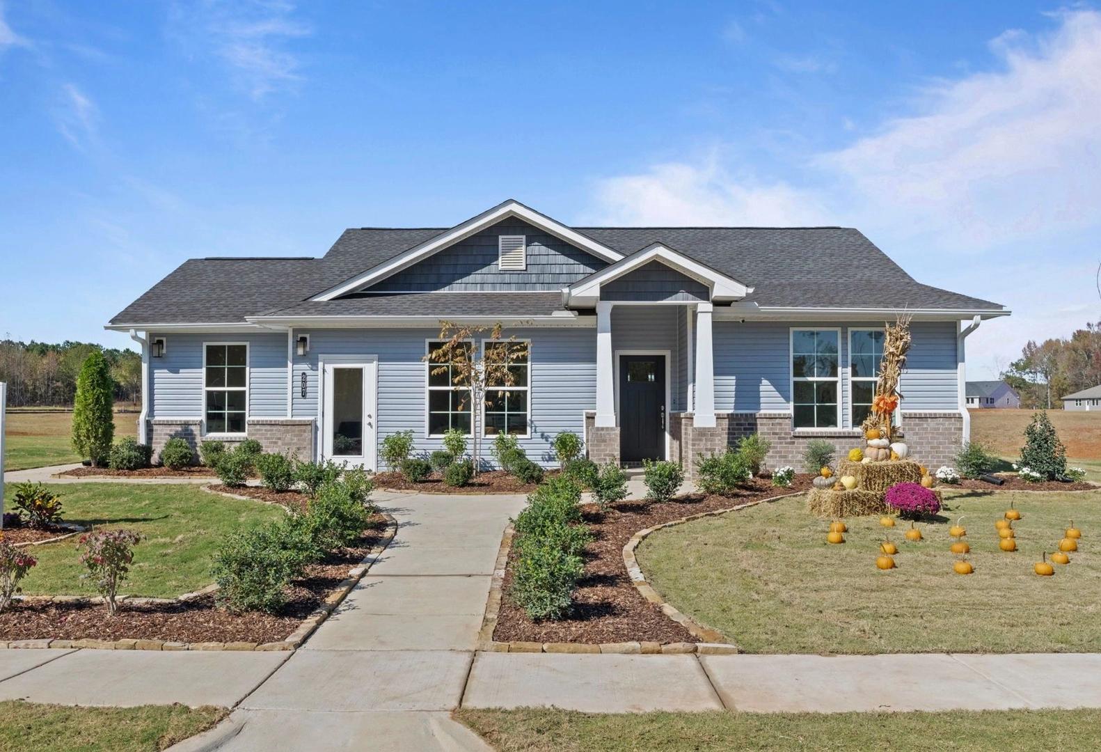 The Phoenix single-story home exterior in Perry, GA: blue siding, gabled shingle roof, landscaped yard with pathway and sign