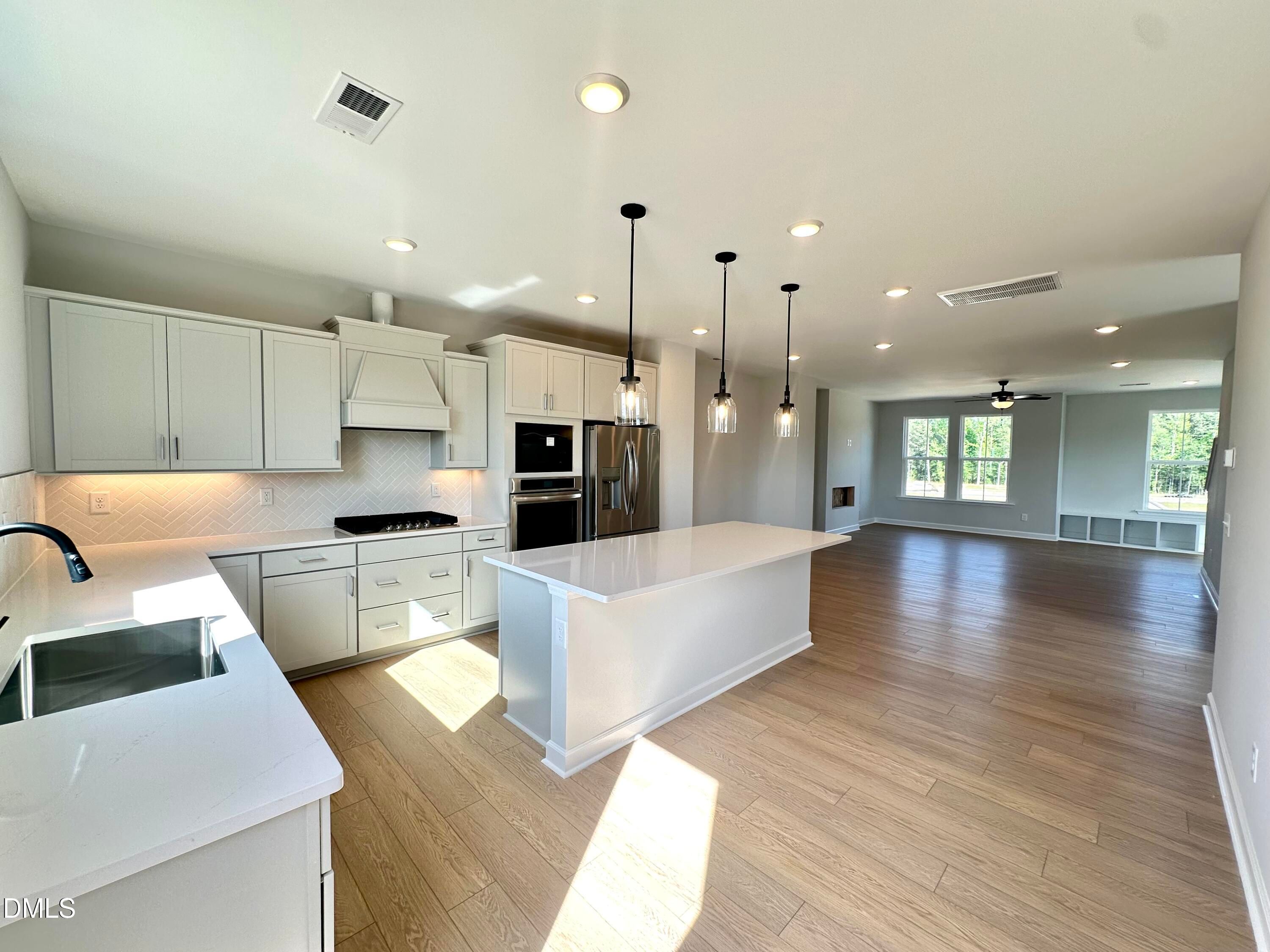 Modern open-concept kitchen with white shaker cabinets, quartz island, stainless appliances in Davidson Homes The Avery, Knightdale, NC